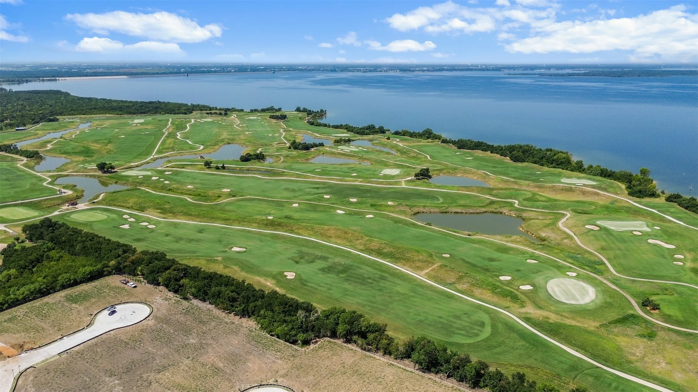 Expansive golf course terrain featuring multiple greens, sand traps, and water features