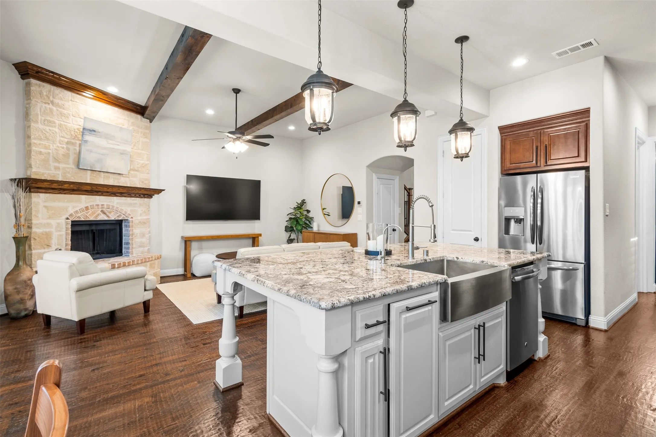 Open-concept living area featuring a kitchen island with a farmhouse sink, granite countertops, and pendant lighting