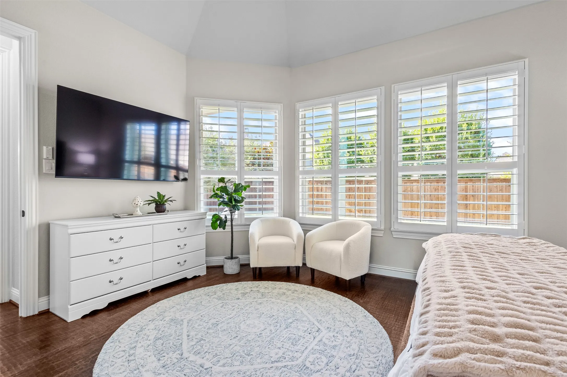 Interior room featuring wood-finish flooring, three large windows with white louvered shutters, light-toned walls, and a recessed ceiling