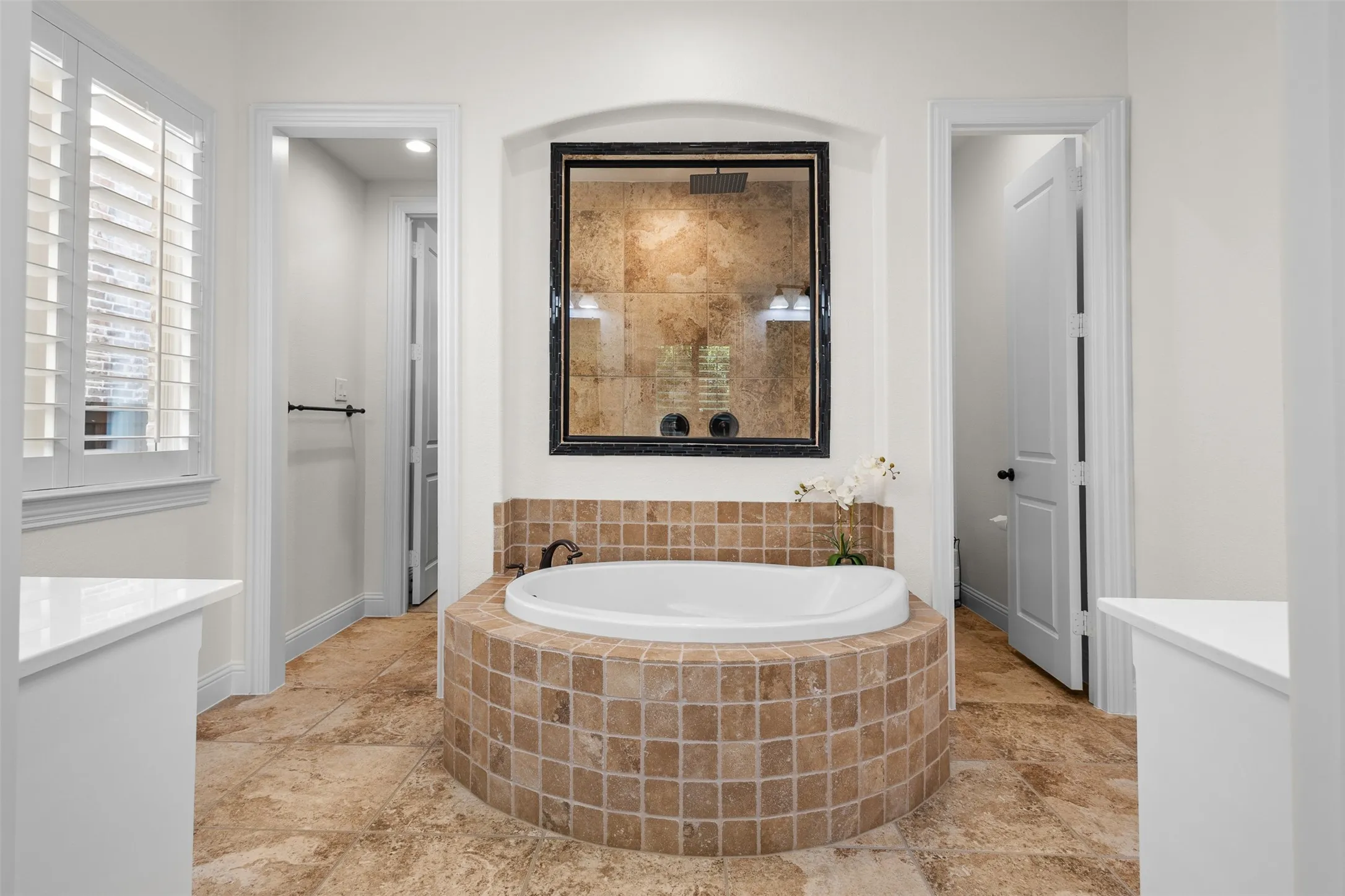 Spacious bathroom featuring a built-in soaking tub with a tiled surround