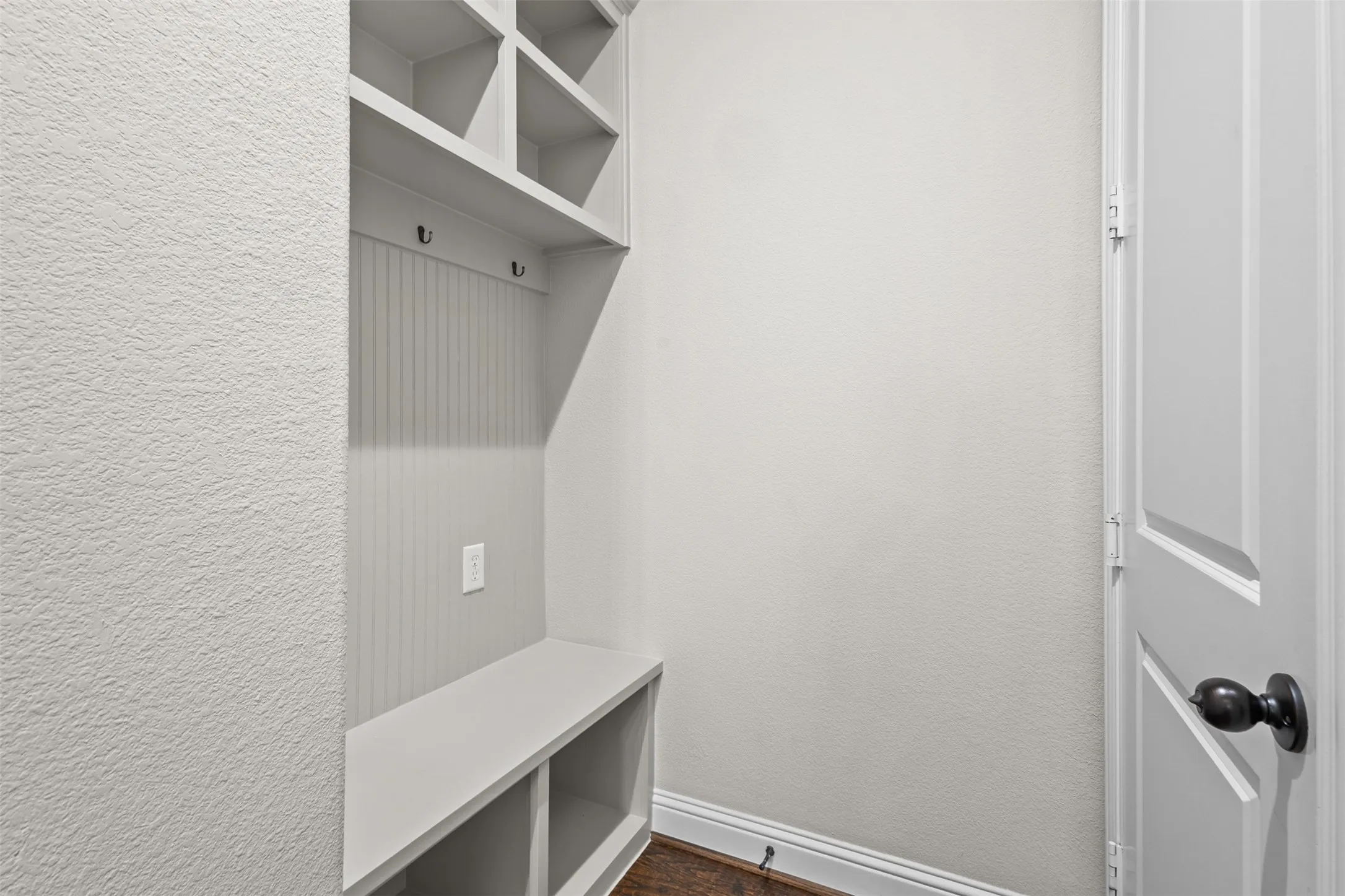 Built-in mudroom bench with storage cubbies and upper shelving, featuring beadboard paneling and integrated coat hooks