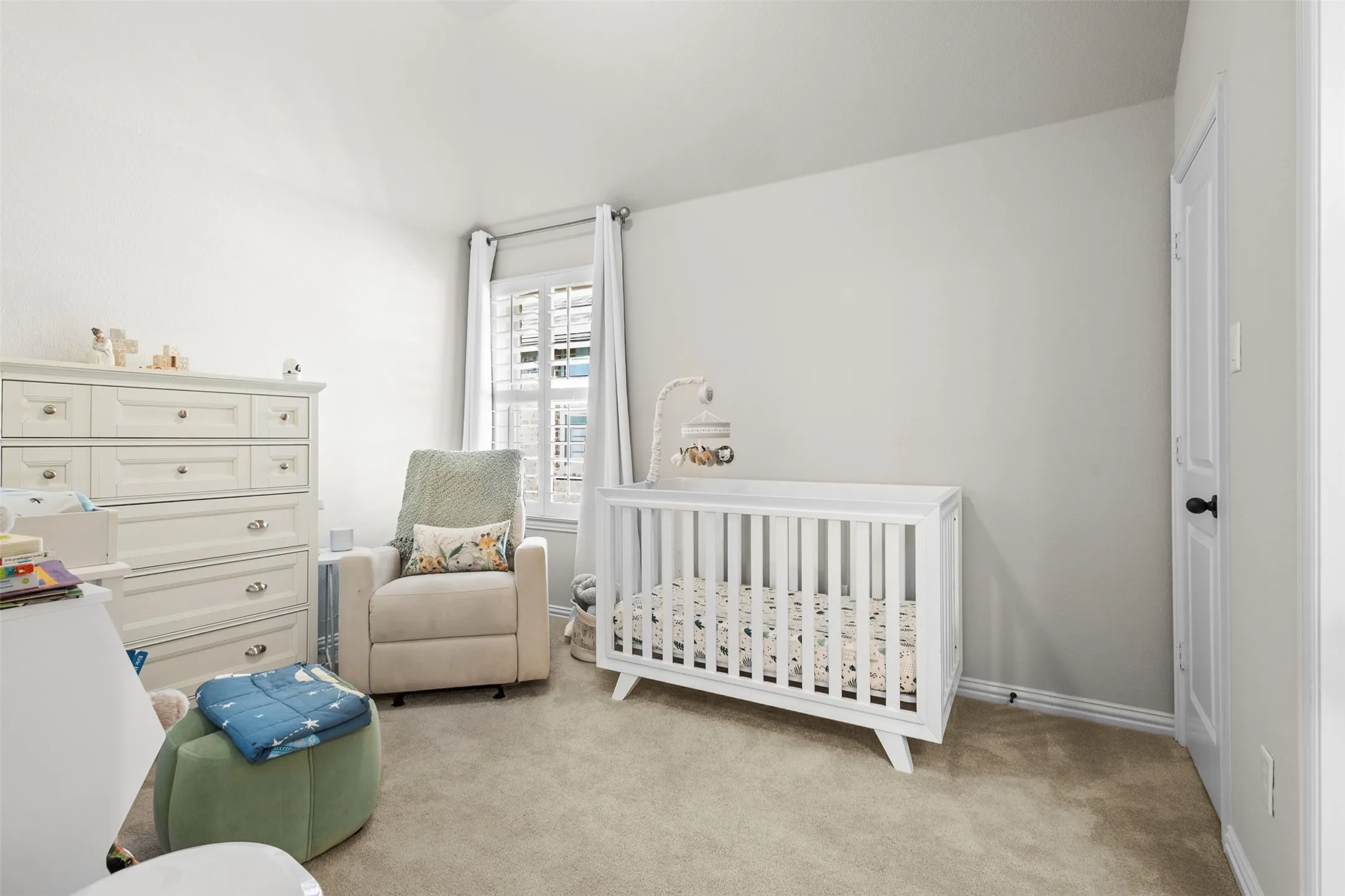 Spacious room featuring vaulted ceilings, neutral-toned carpeting, and a white paneled door with black hardware