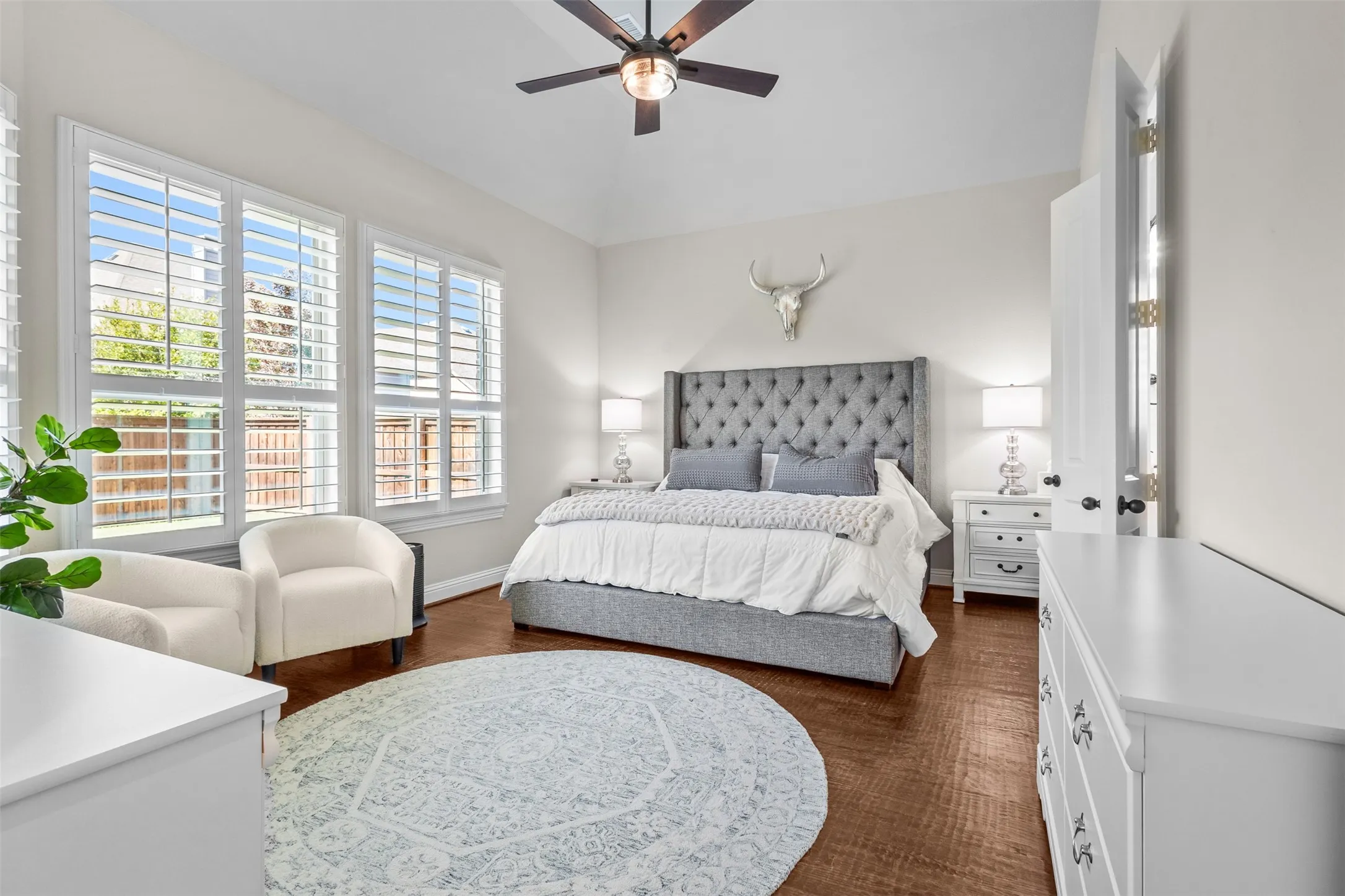 Spacious room featuring vaulted ceilings, wood-finish flooring, and multiple large windows with plantation shutters