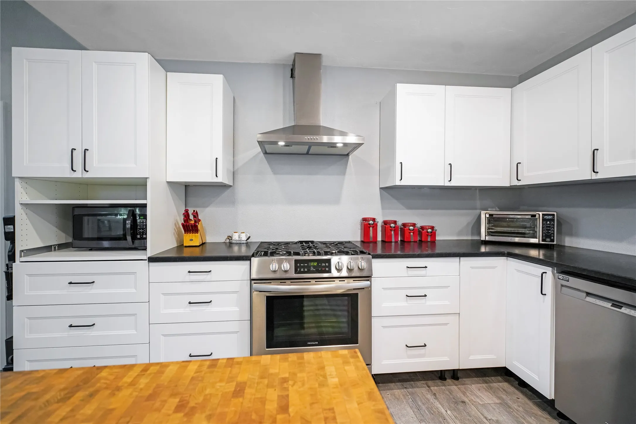 Modern kitchen with white shaker-style cabinetry, dark countertops, and stainless steel appliances