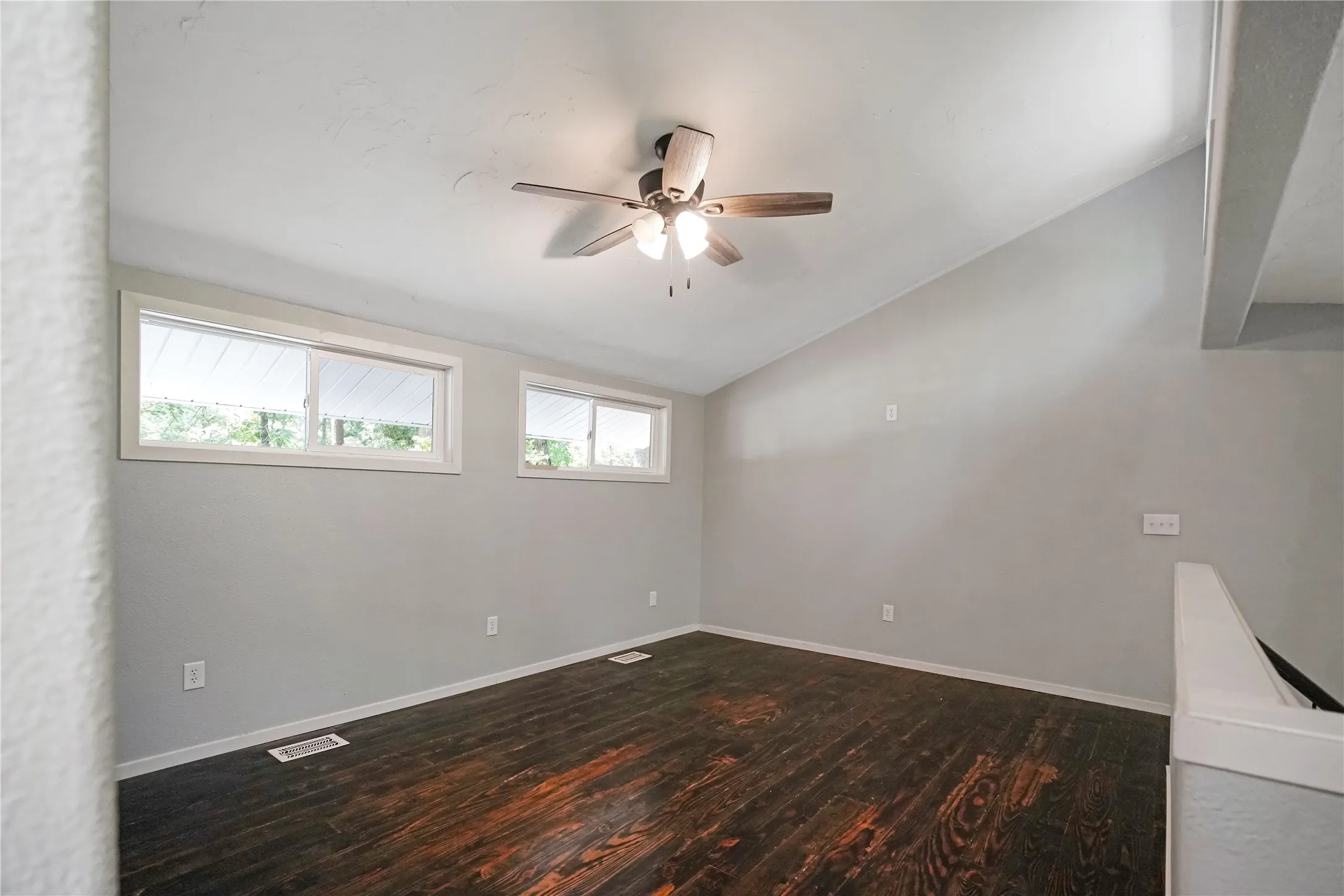 Room featuring vaulted ceilings and rich wood-finish flooring