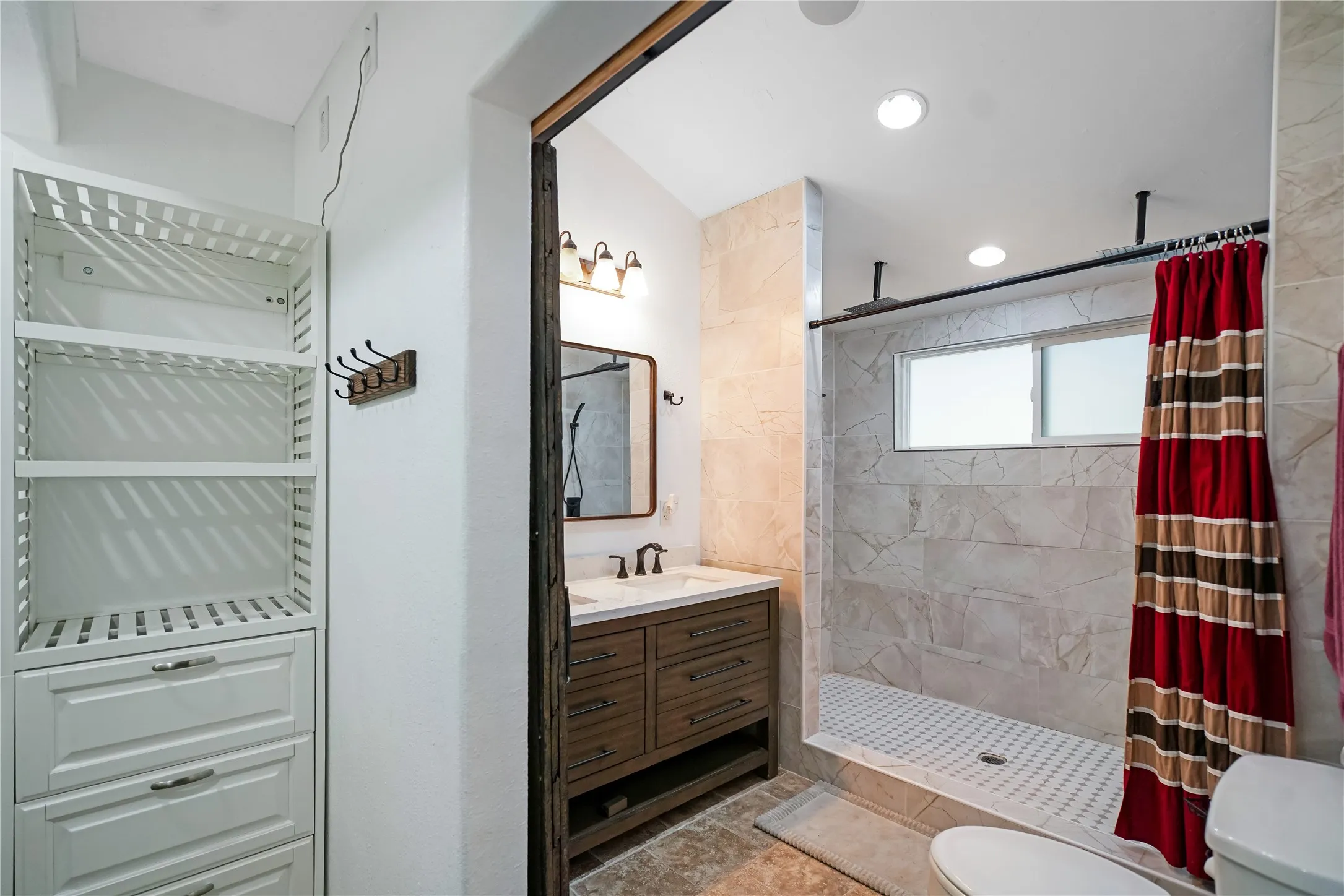 Full bathroom featuring a wood-finish vanity with a white countertop and rectangular undermount sink, a large walk-in shower with tile surround and frosted window, and recessed lighting