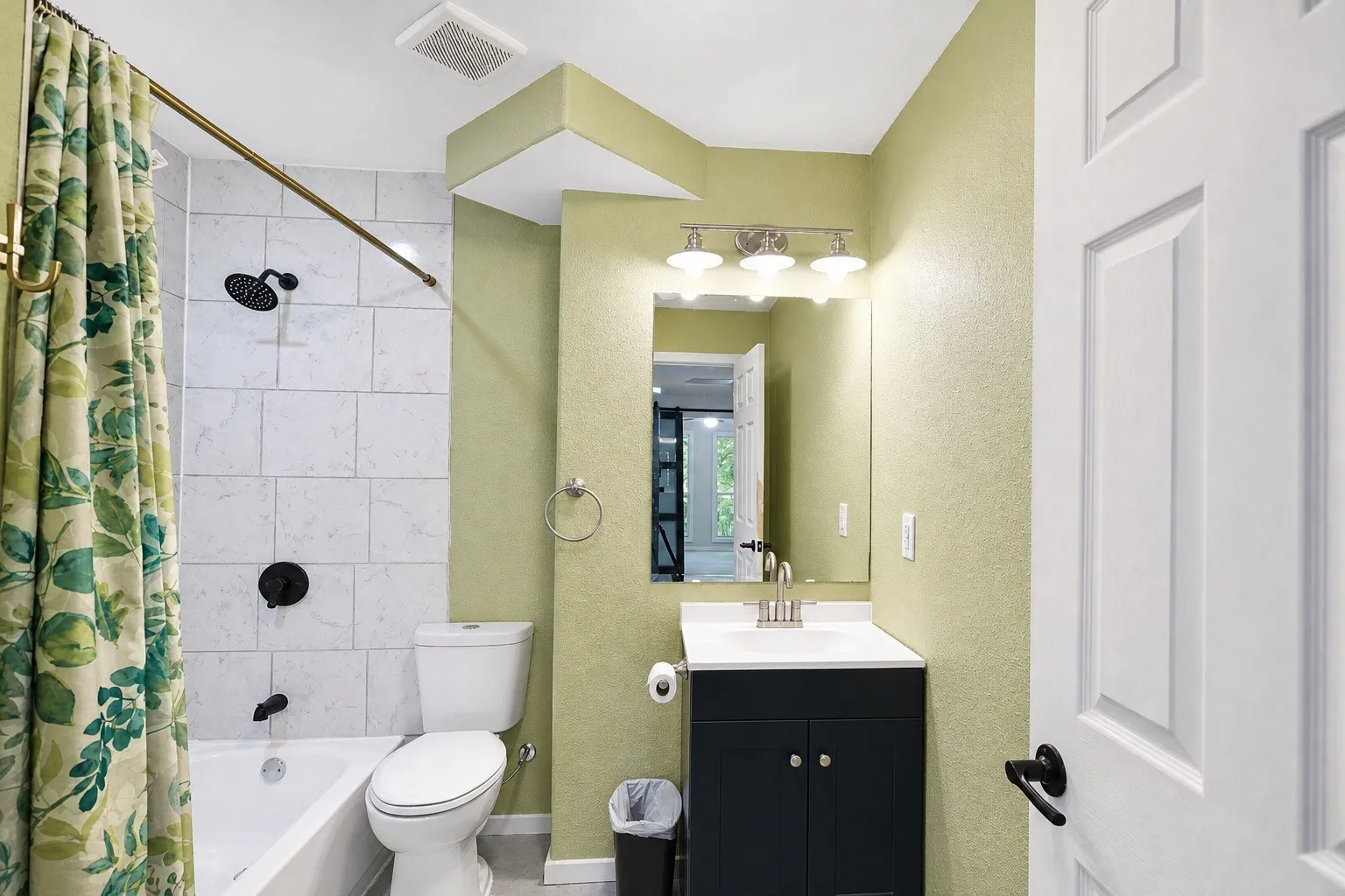 Bathroom featuring a white subway tile shower surround, matte black shower fixtures, a white vanity with a dark cabinet base, a mirrored medicine cabinet, and a panel-style door