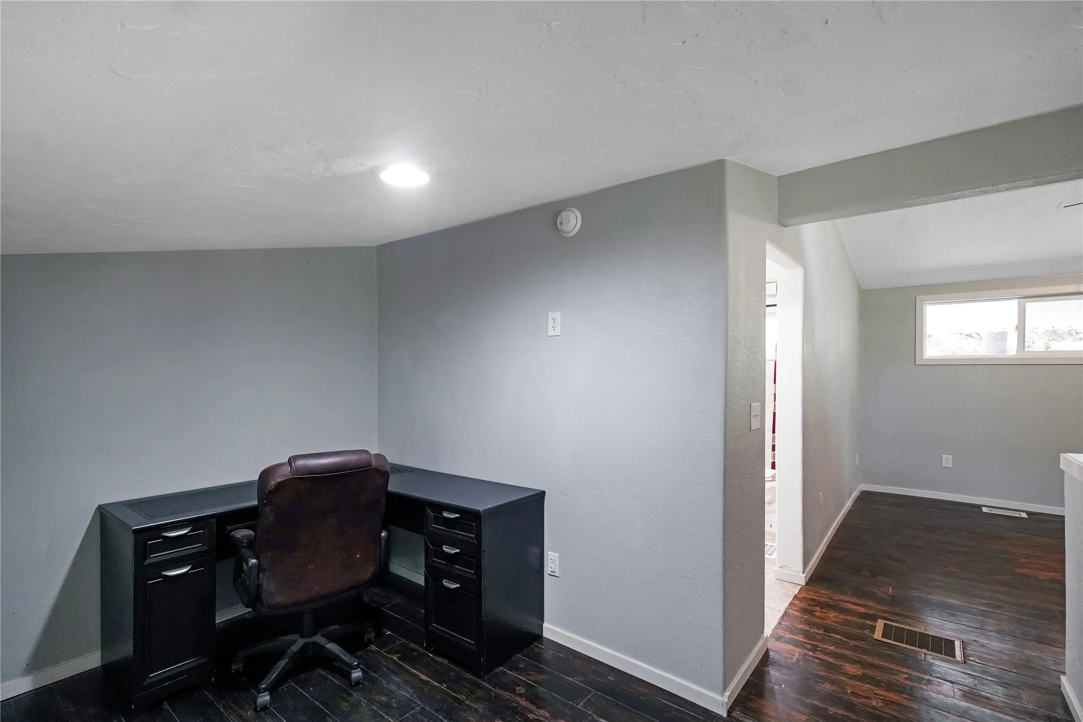 Dedicated office nook with built-in desk cabinetry, recessed lighting, and dark wood-finish flooring