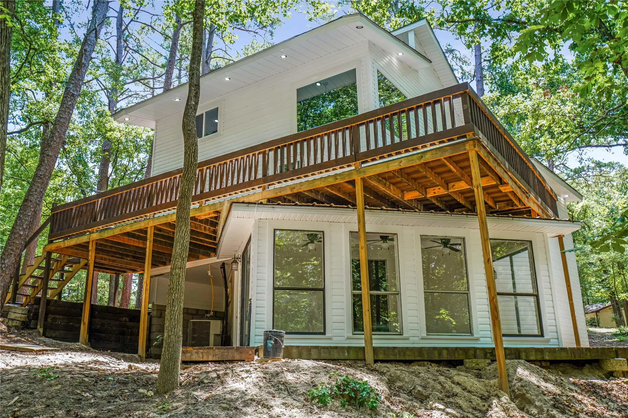 Multi-level residence featuring a white siding exterior and a prominent upper-level wood deck with dark-stained railings