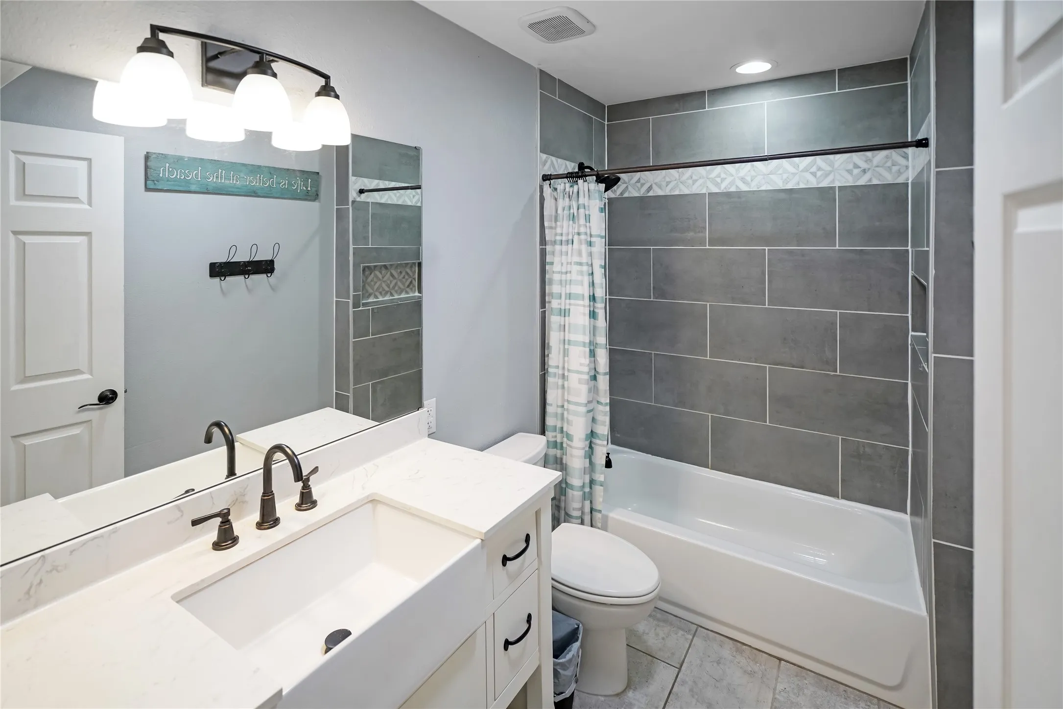 Bathroom featuring a white vanity with an integrated rectangular sink, dark bronze-finish fixtures, and a large wall mirror