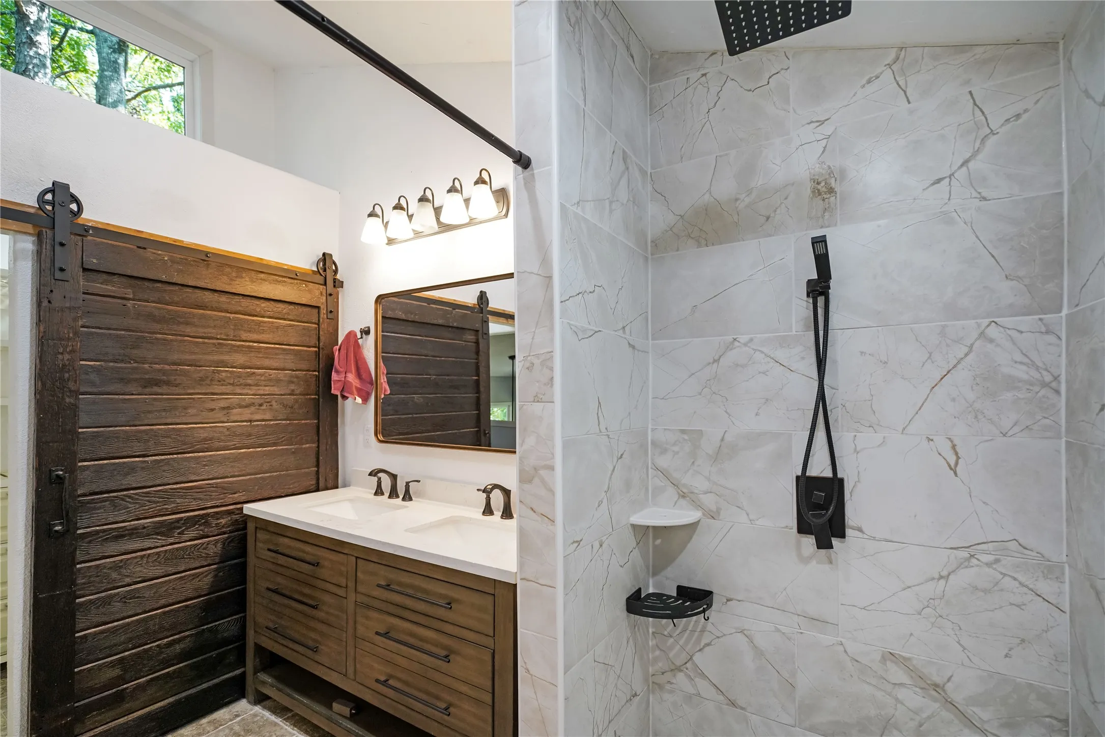Bathroom featuring a dual vanity with white countertops, wood cabinetry, and a framed mirror