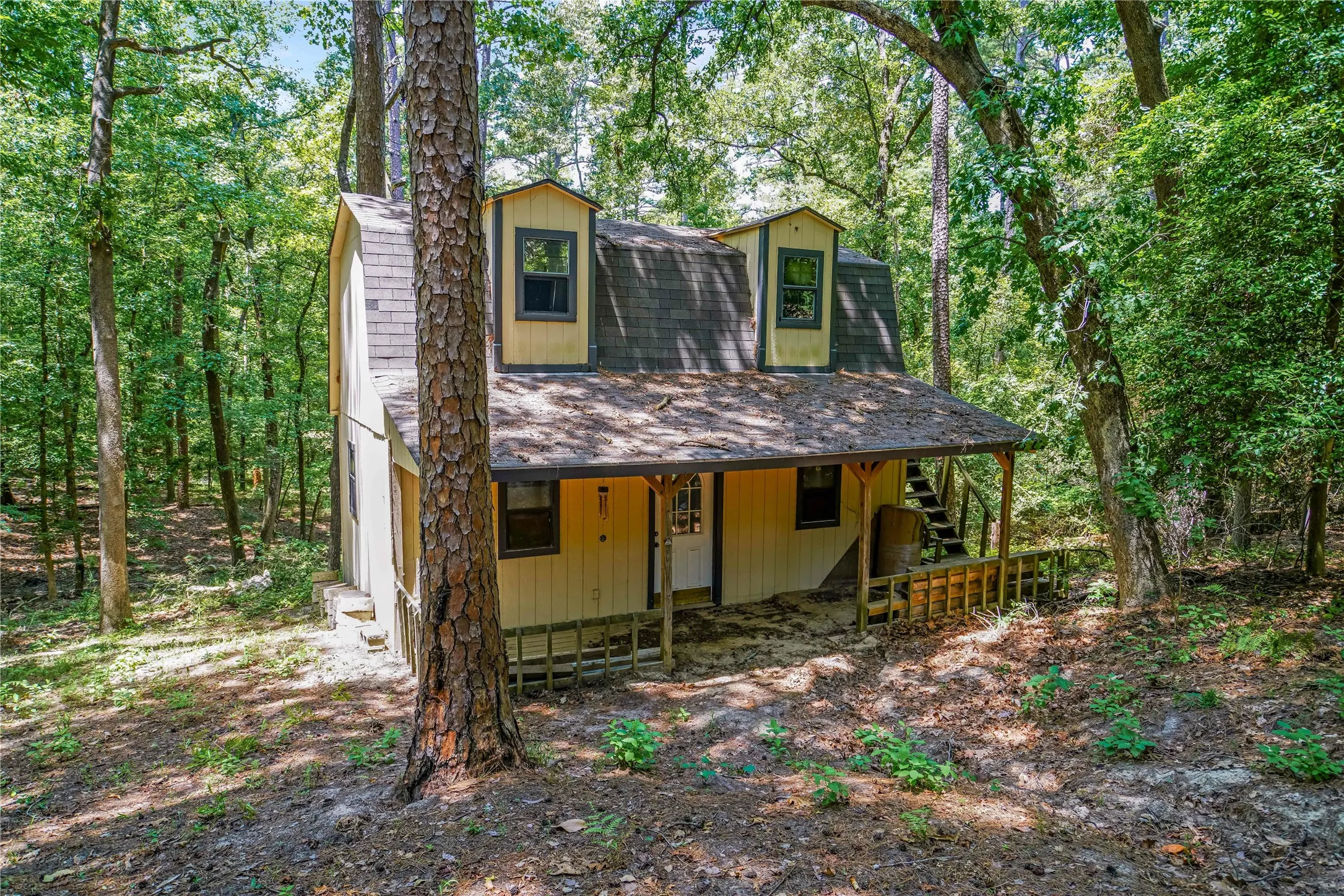 Two-story residence featuring dormer windows, a covered front porch, and a wooden deck with railing