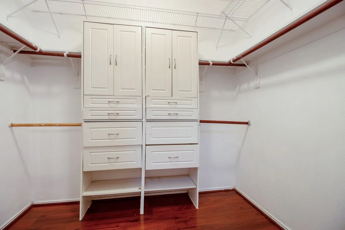 Walk-in closet featuring built-in cabinetry, multiple drawers, shelving, and dedicated hanging rods