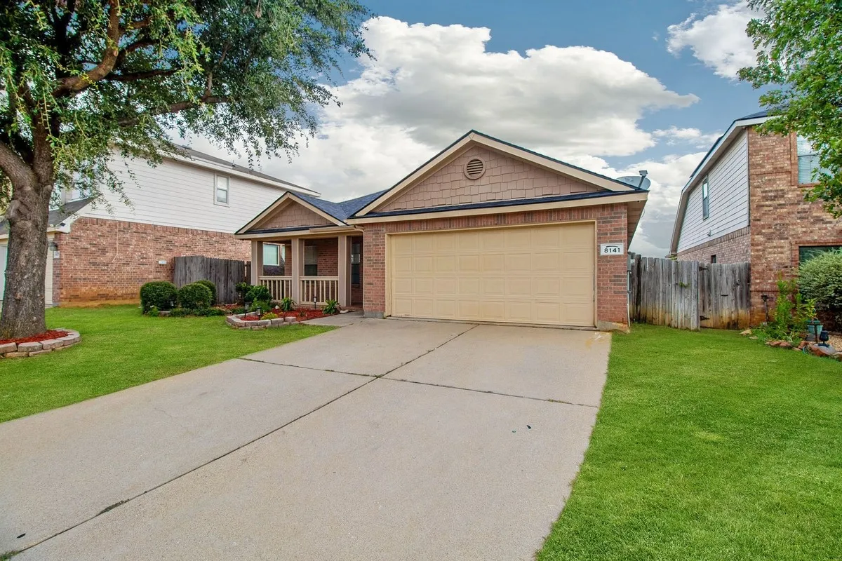 Brick and siding exterior featuring an attached garage, covered front porch with railings, and established landscaping with mature trees
