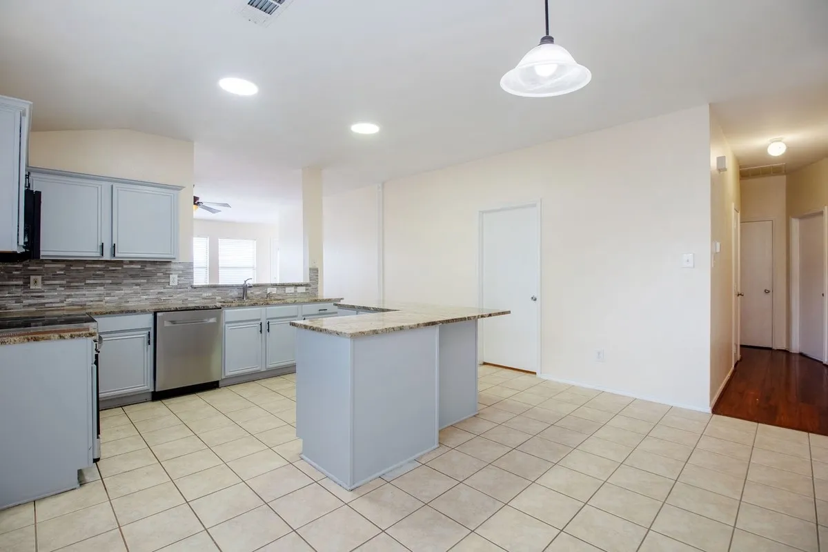 Kitchen featuring light cabinetry, granite countertops, stainless steel appliances, and a mosaic tile backsplash