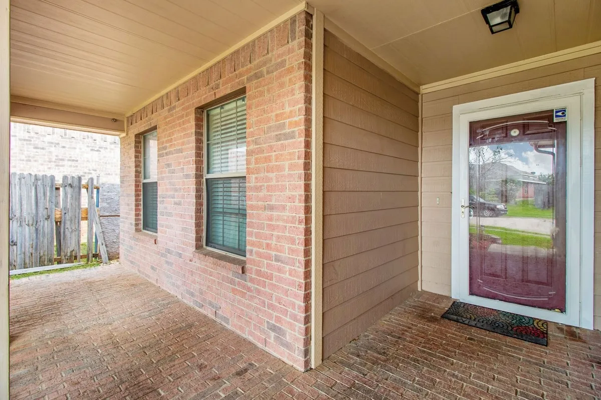 Covered front porch featuring a brick facade, siding accents, and a brick paver floor