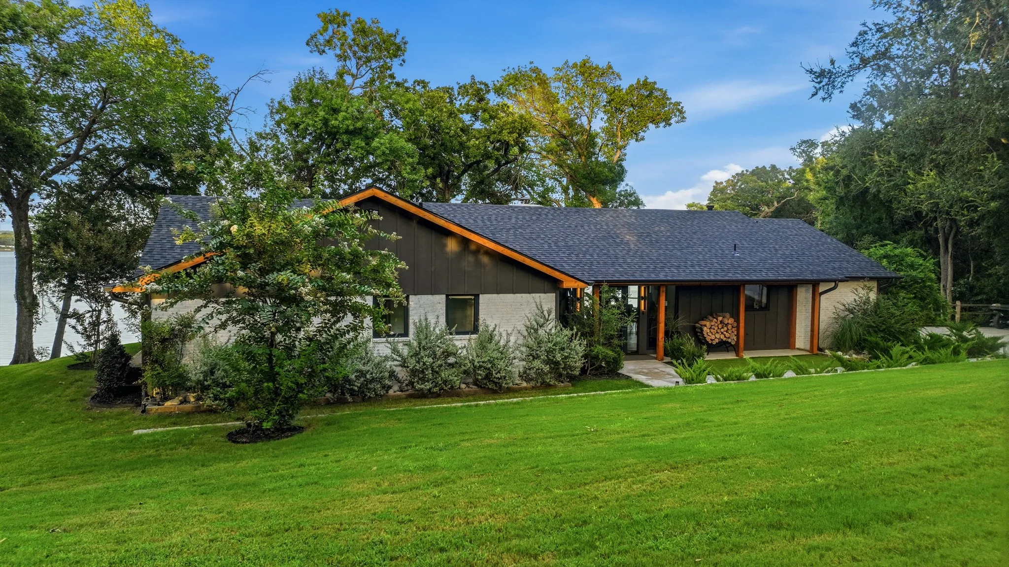 Contemporary ranch-style residence featuring a dark shingle roof and a combination of light-colored stucco and dark horizontal siding