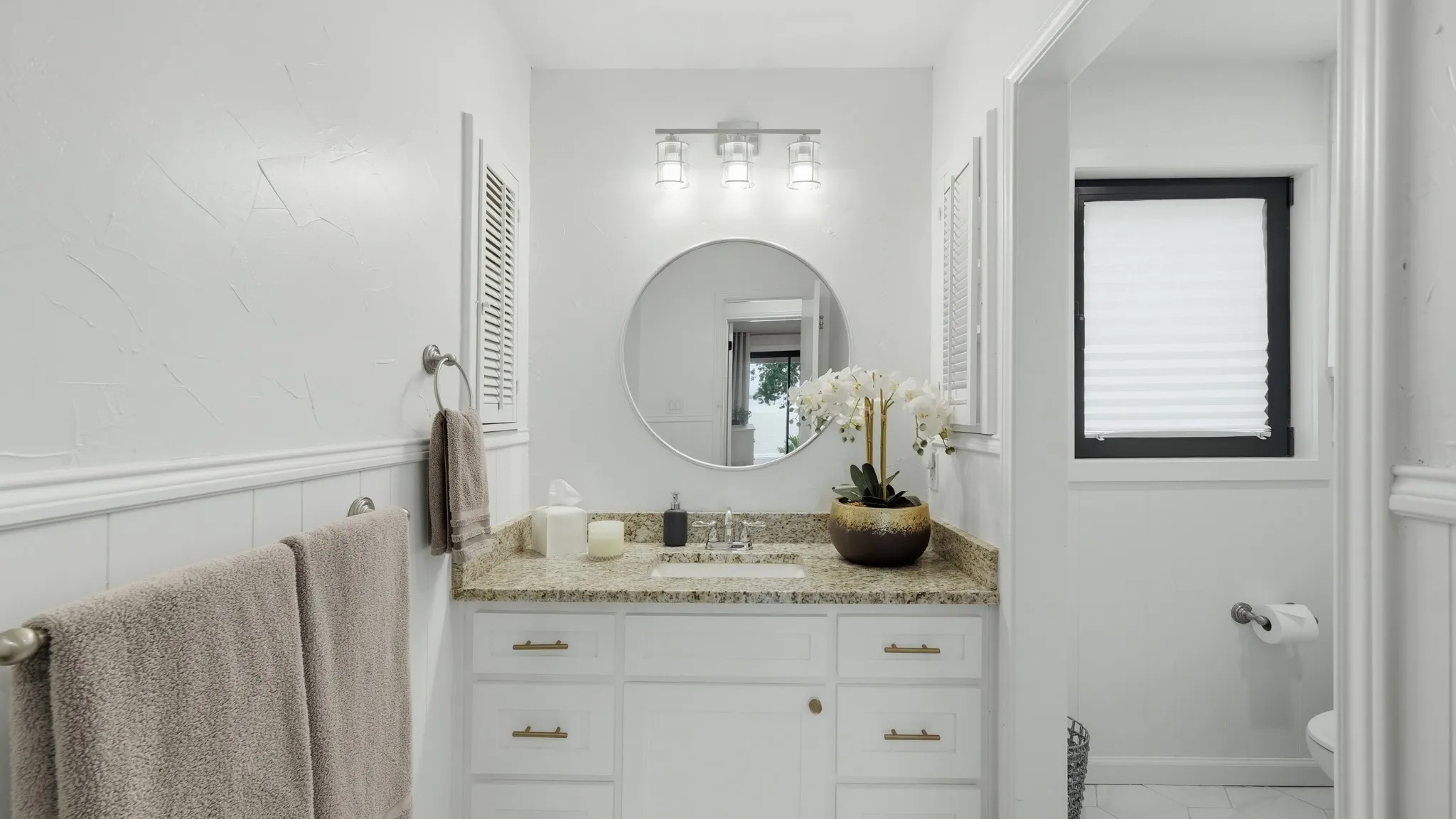 Bathroom vanity with a granite-style countertop, undermount sink, and brushed nickel faucet