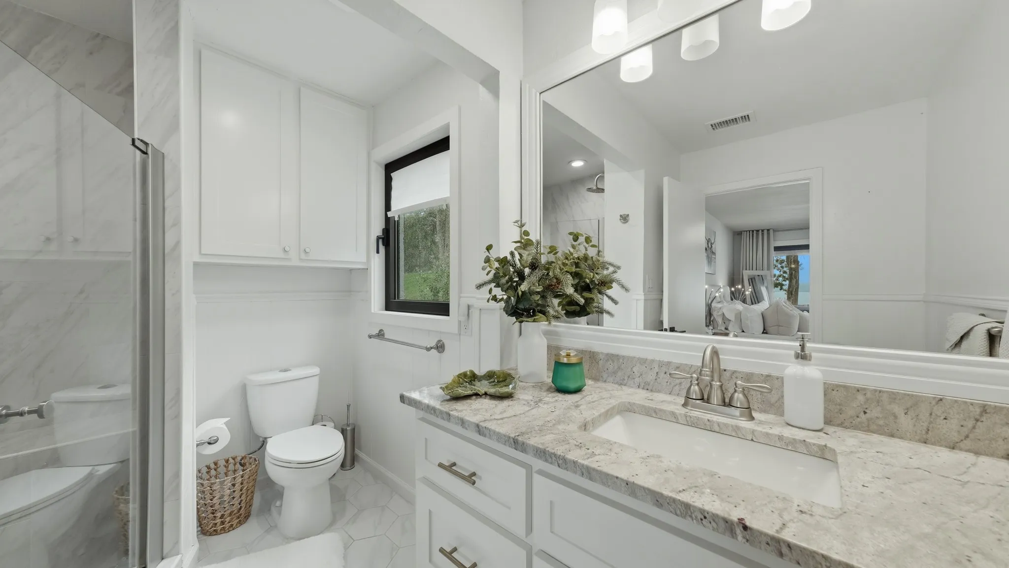 Bathroom featuring a light-toned vanity with an integrated sink, a substantial wall-mounted mirror, and a three-light fixture