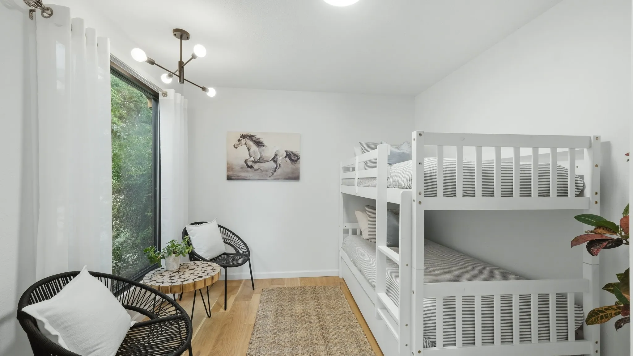 Bright interior space featuring a large window, light wood-finish flooring, a contemporary ceiling light fixture, and white wall finishes