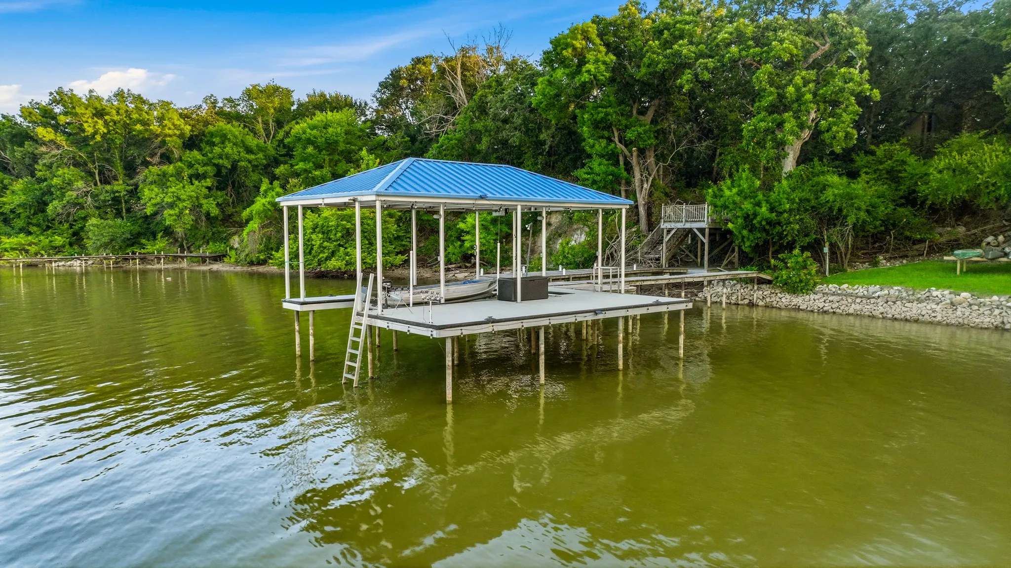Covered dock with a blue metal roof, featuring a boat lift and an attached ladder