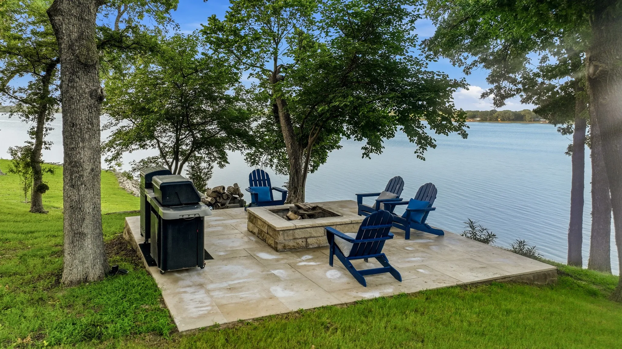 Waterside patio featuring a stone-clad fire pit and ample seating