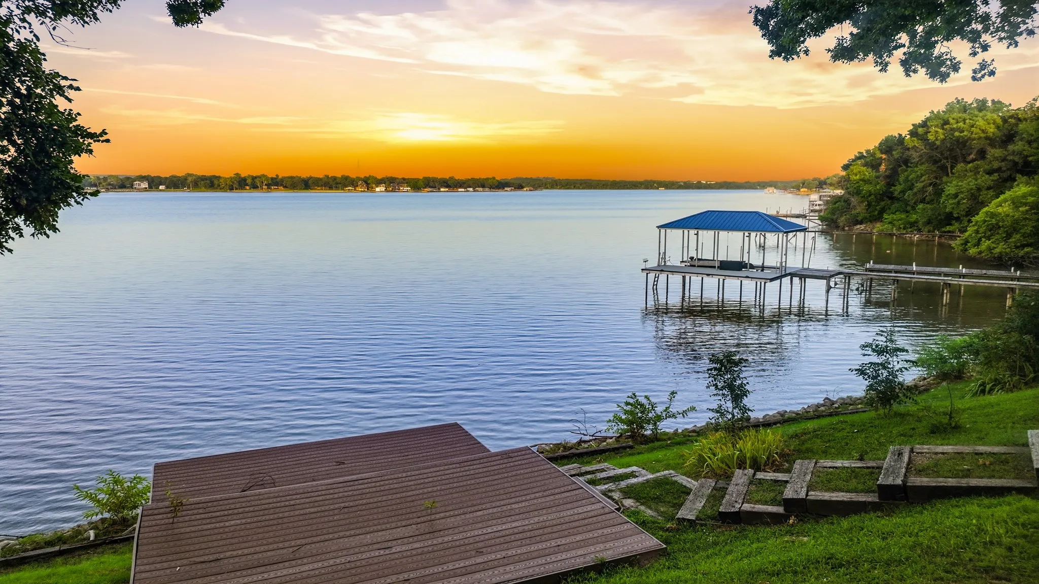 Waterfront property with a private boat dock, covered boat slip, and tiered landscaping descending to the water