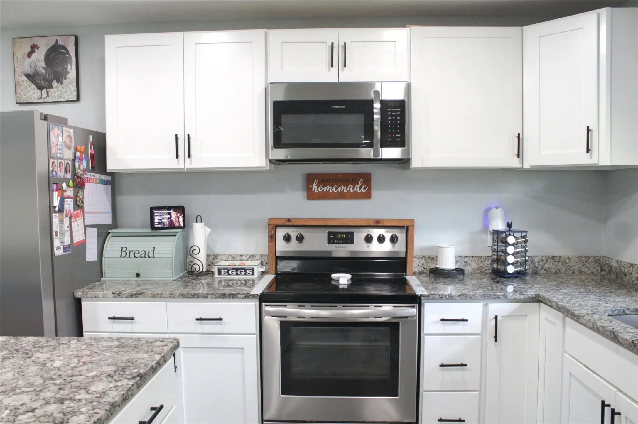 Kitchen featuring white shaker-style cabinetry with matte black hardware, stainless steel appliances, and speckled countertops