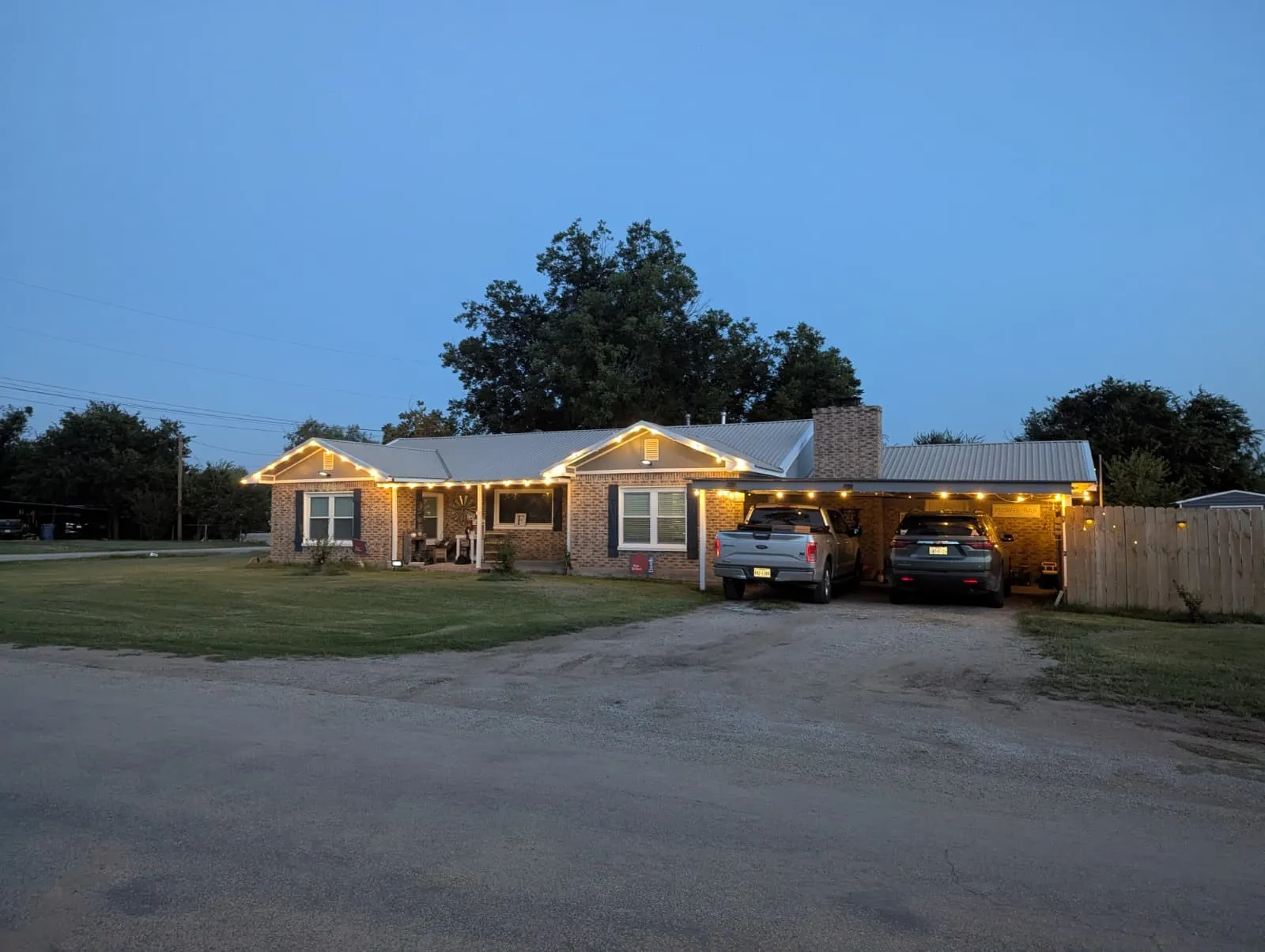Brick exterior with a metal roof, covered front porch, attached carport, and a brick chimney