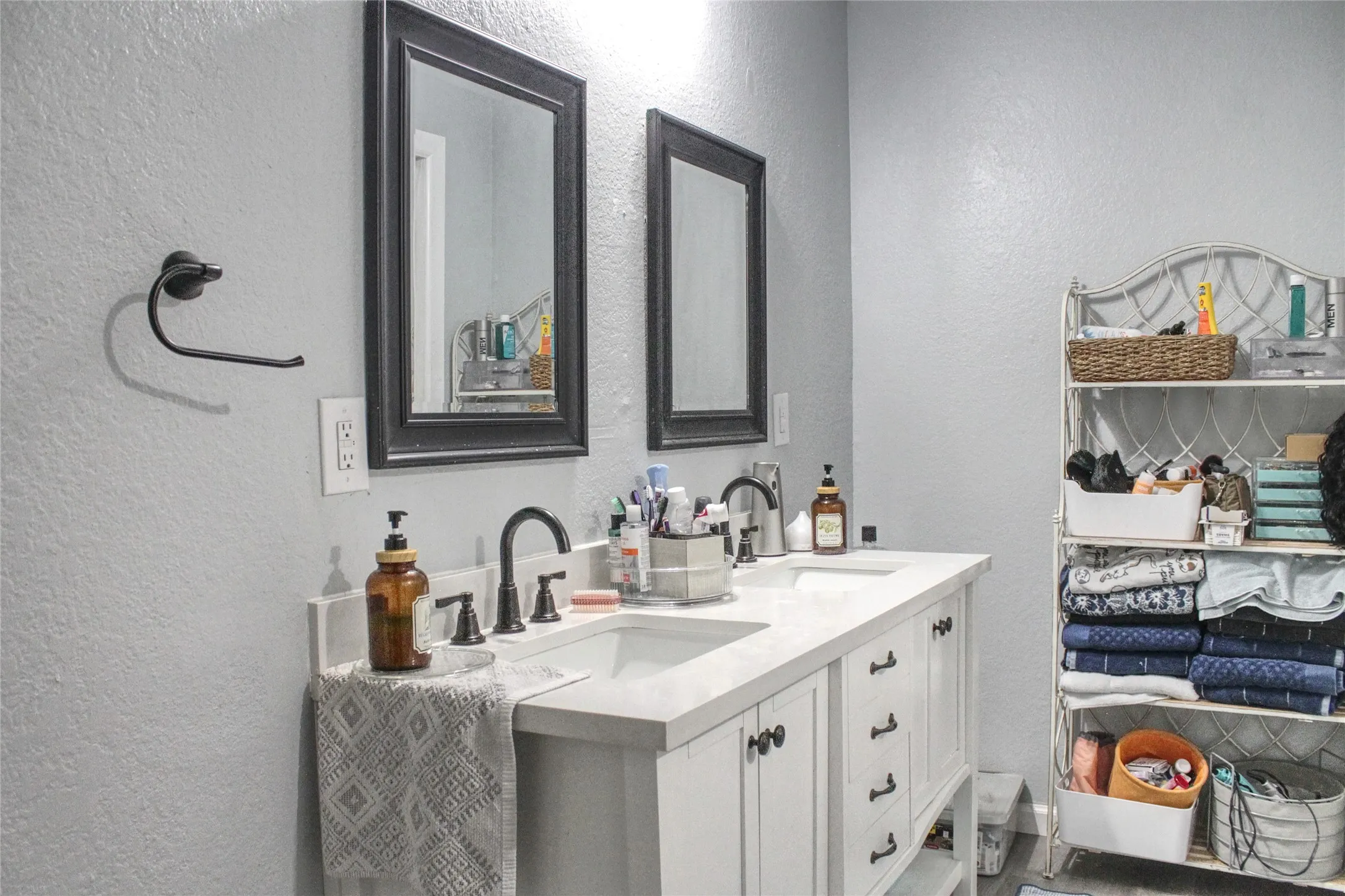 Double vanity with integrated sinks, white cabinetry, dark hardware, and two framed mirrors