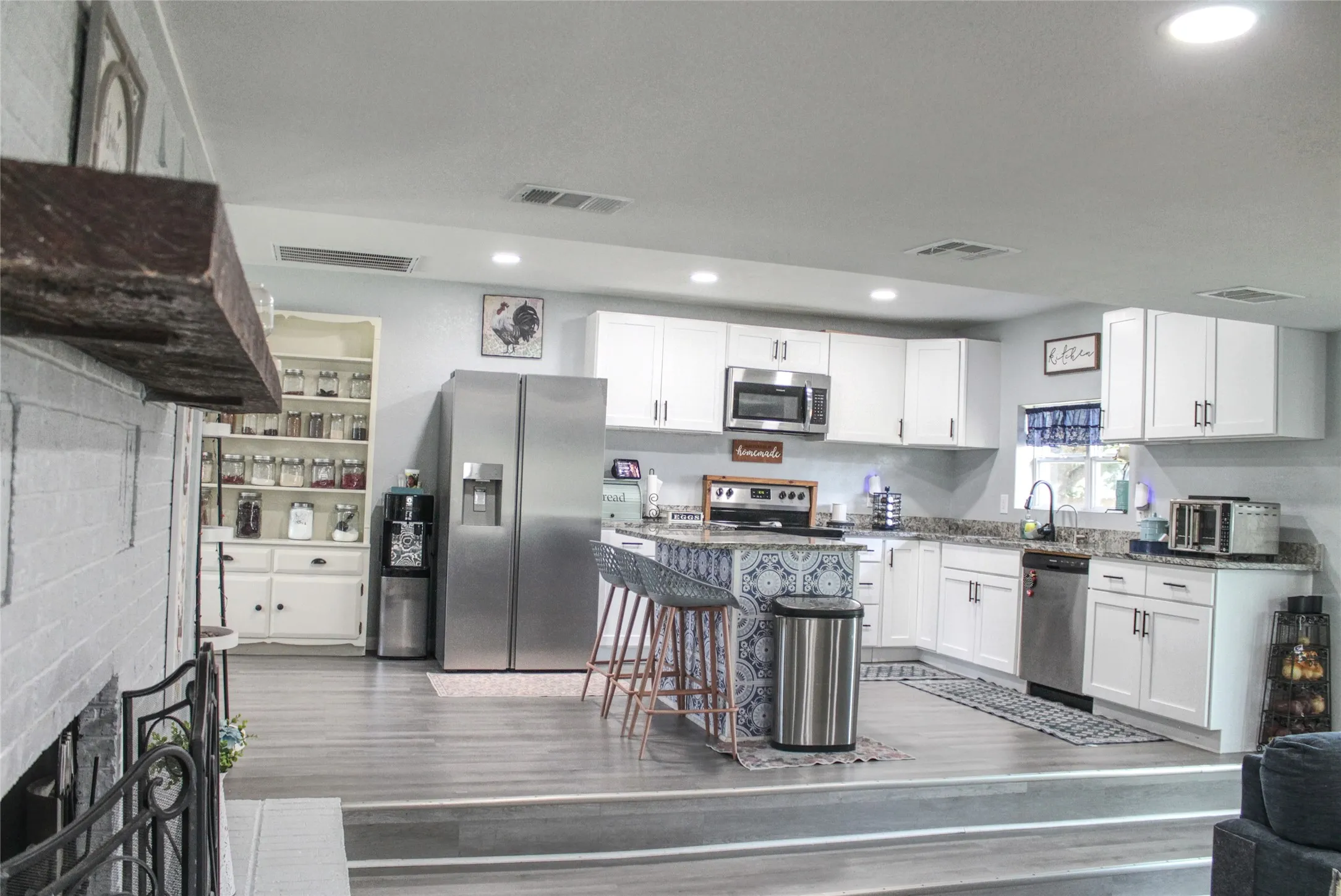 Contemporary kitchen featuring white cabinetry, stainless steel appliances, a center island with bar seating, and wood-finish flooring