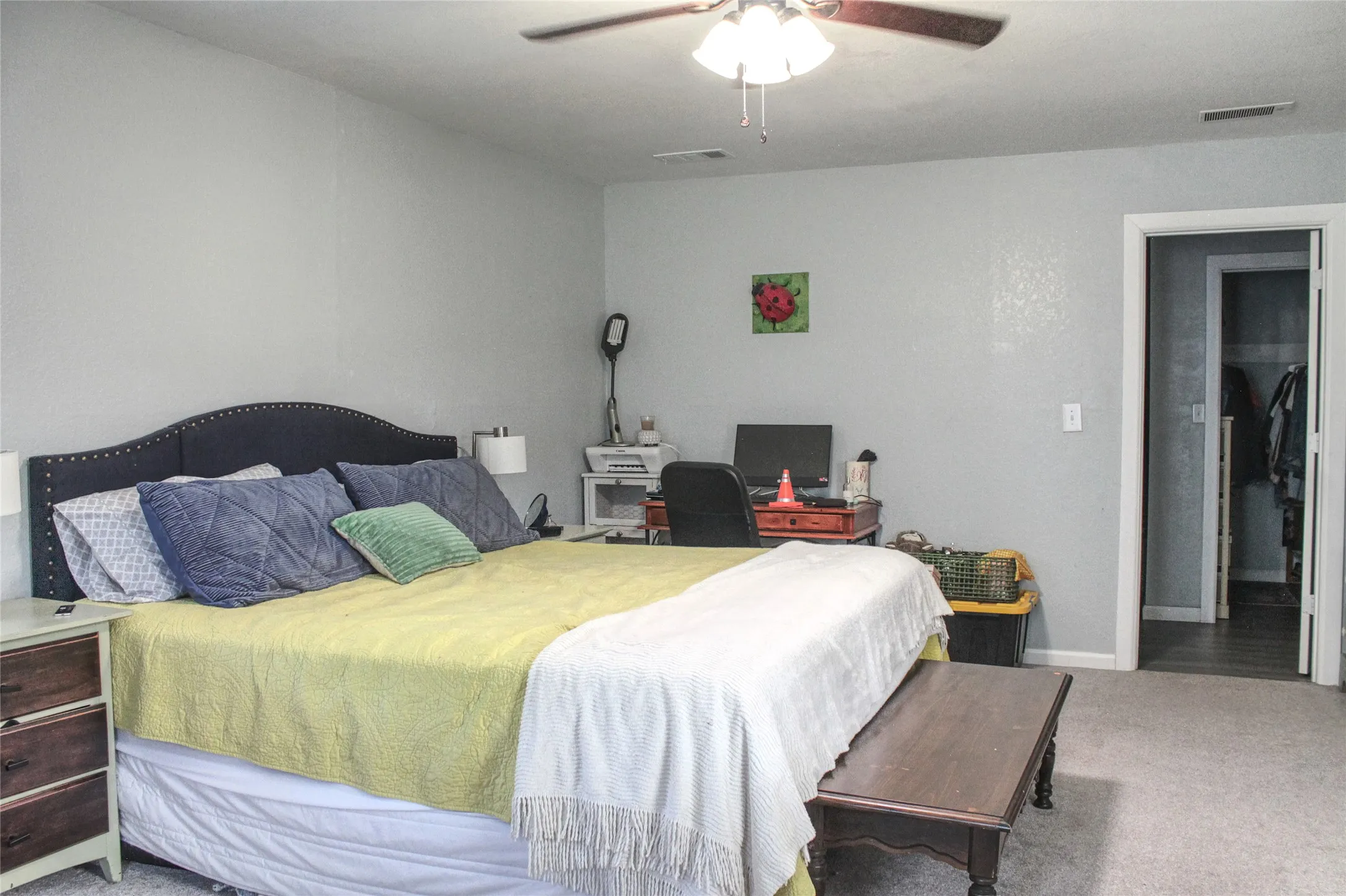 Spacious bedroom featuring light grey walls, carpeted flooring, and a ceiling fan with integrated lighting