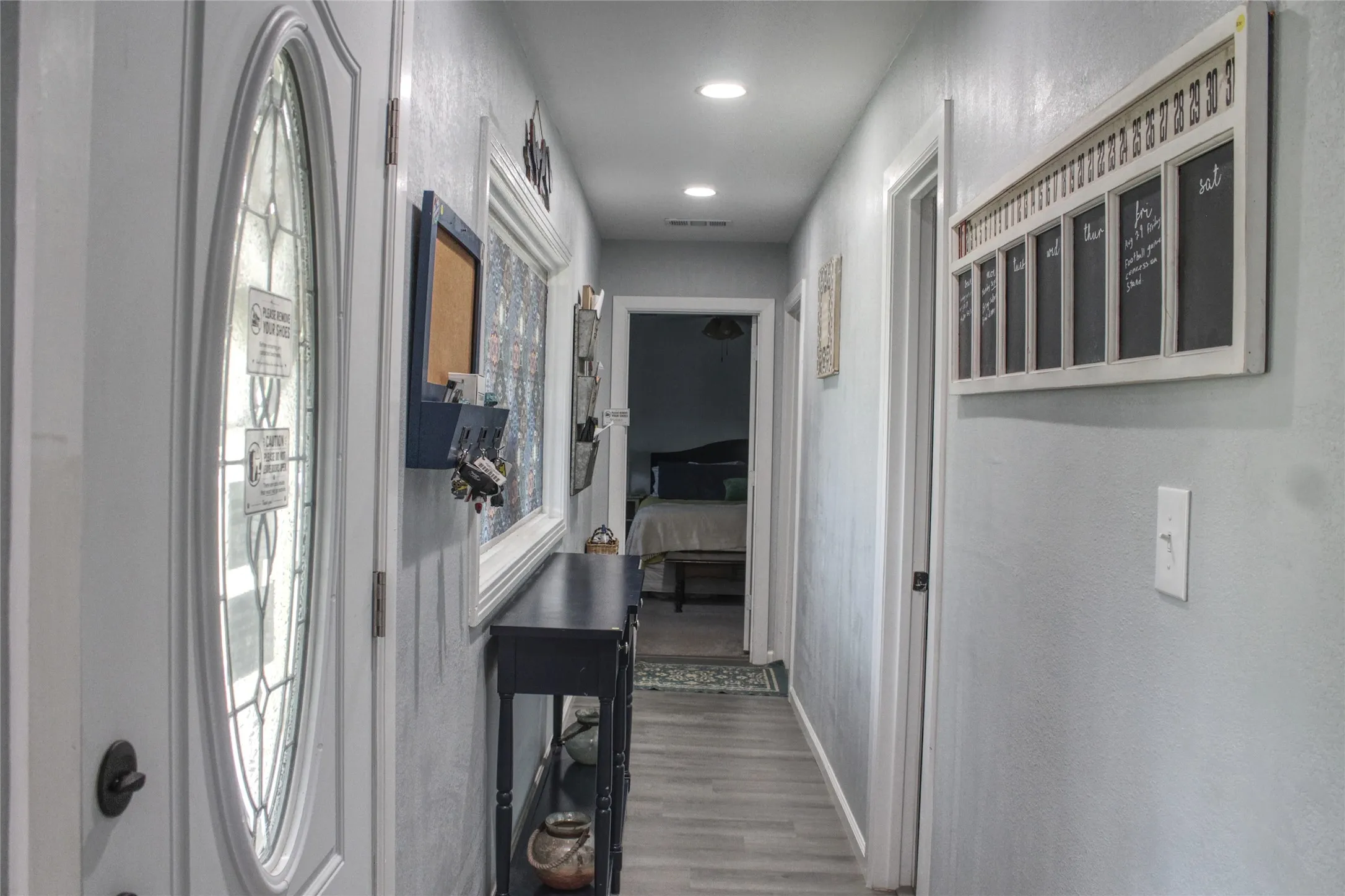 Entryway featuring a decorative oval-paneled door with frosted glass, recessed ceiling lighting, and wood-finish flooring