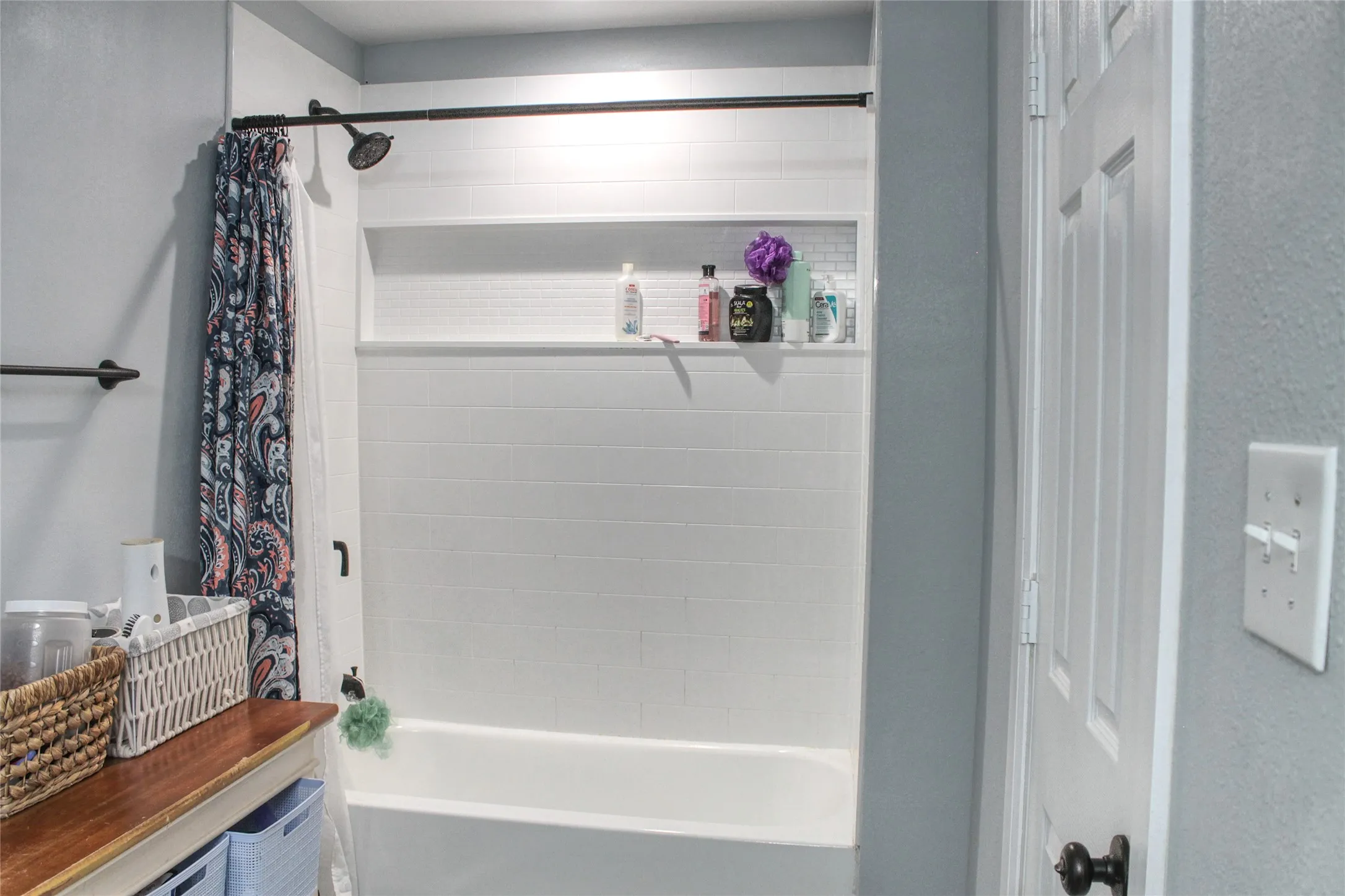 White subway tile shower surround with a built-in niche, dark bronze shower fixture, and white bathtub
