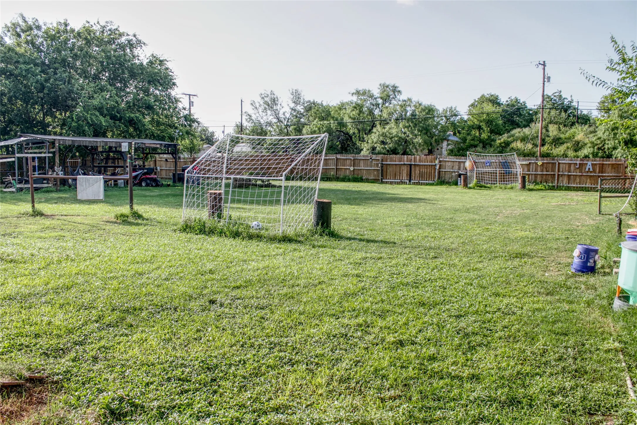 Expansive grass lawn featuring a wood privacy fence and a separate covered structure