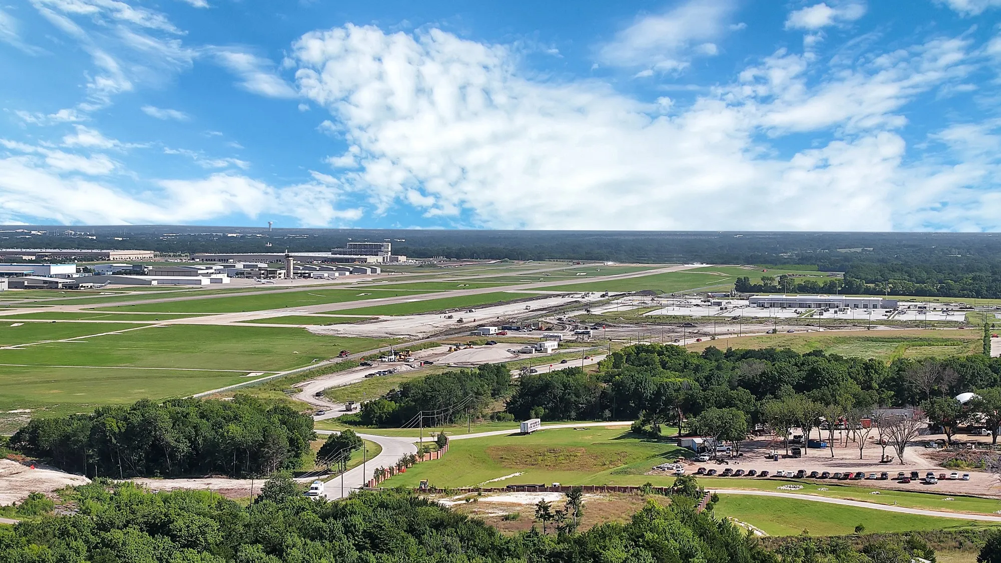 Aerial perspective showcasing extensive green spaces, multiple runways, and various industrial structures