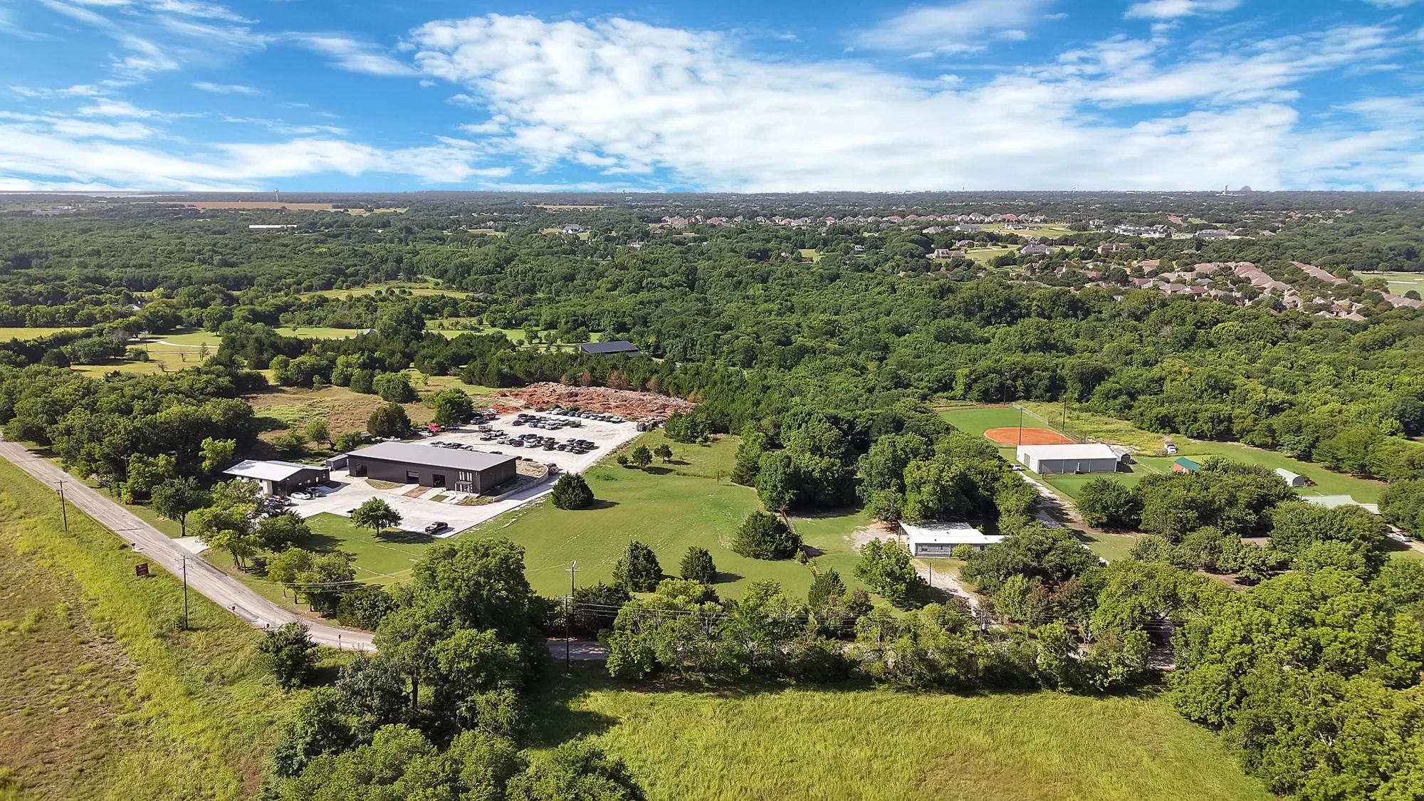 Expansive lot featuring a large commercial building with a black roof and ample paved parking