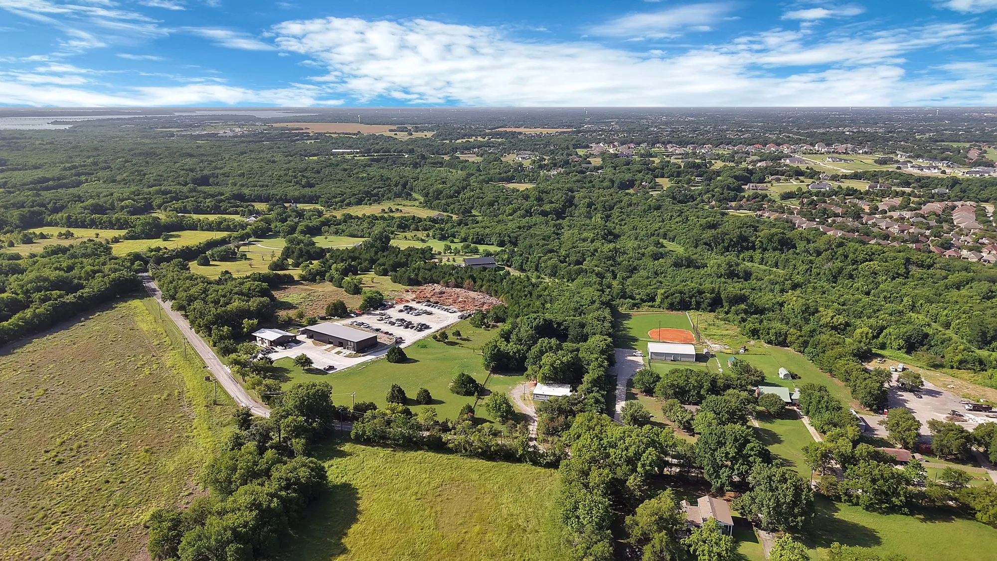 Expansive aerial view showcasing diverse terrain including wooded areas and open fields