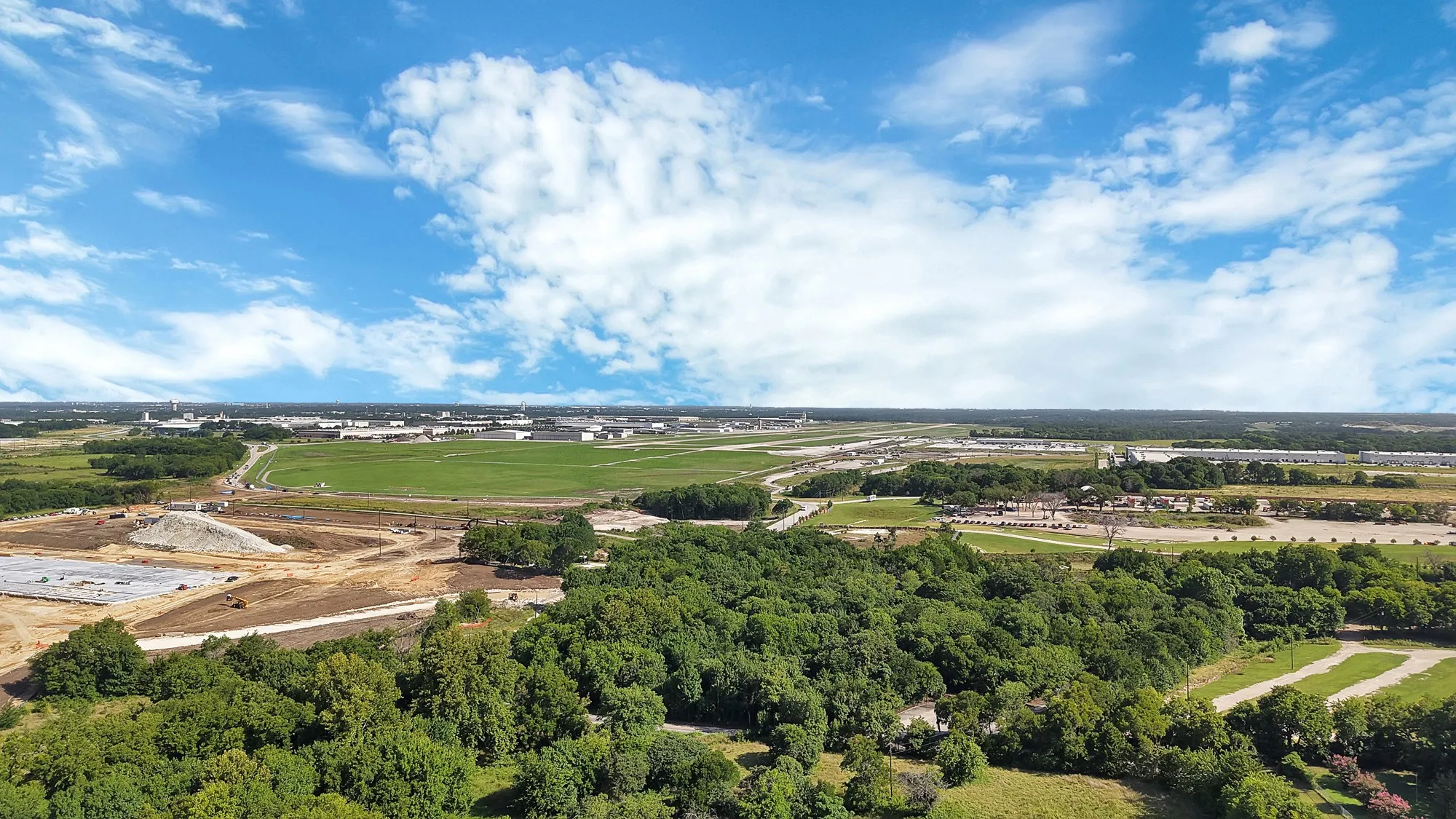 Expansive aerial view showcasing verdant tree lines and developing land