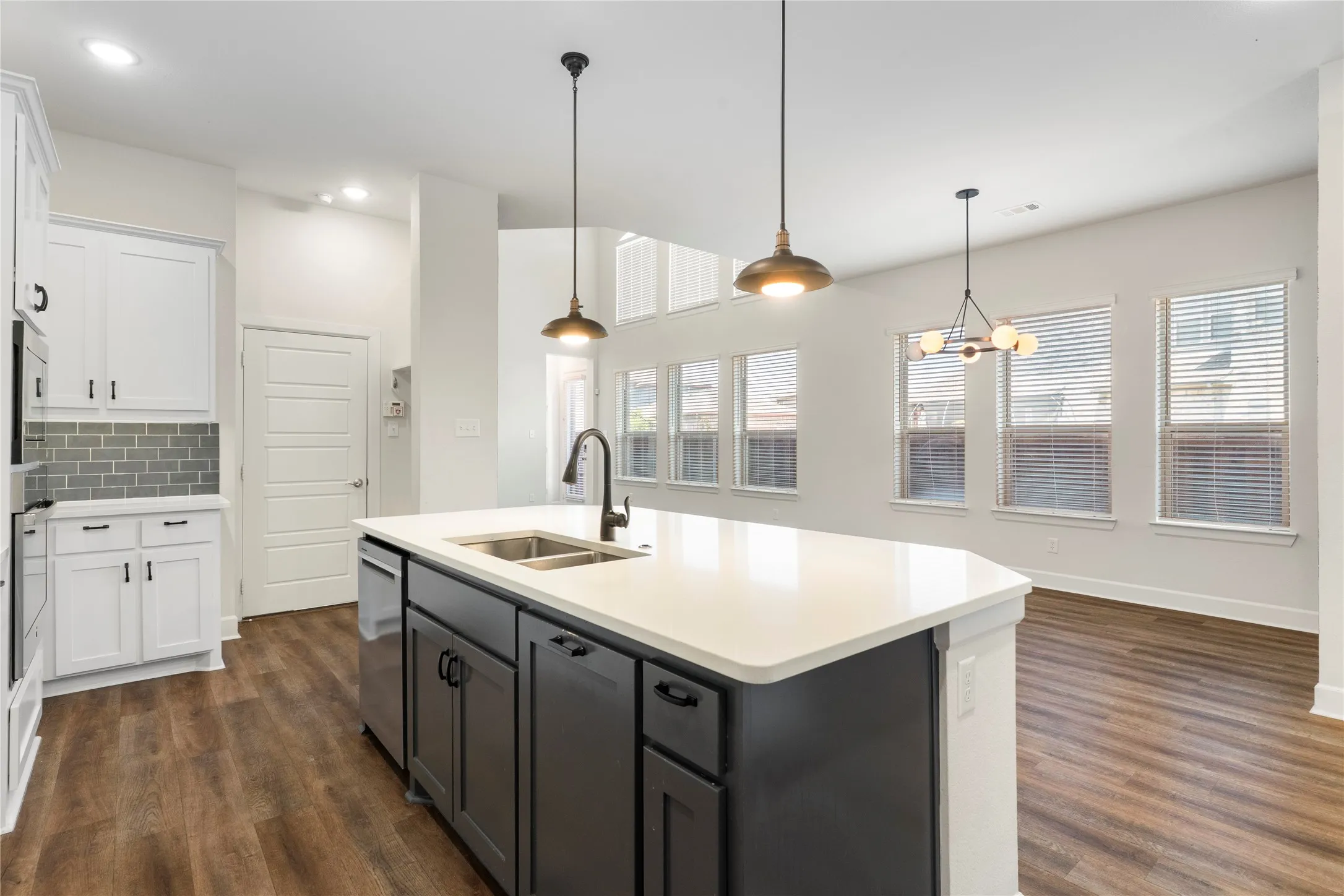 Kitchen island with an undermount double-basin sink, a matte black gooseneck faucet, and integrated dishwasher