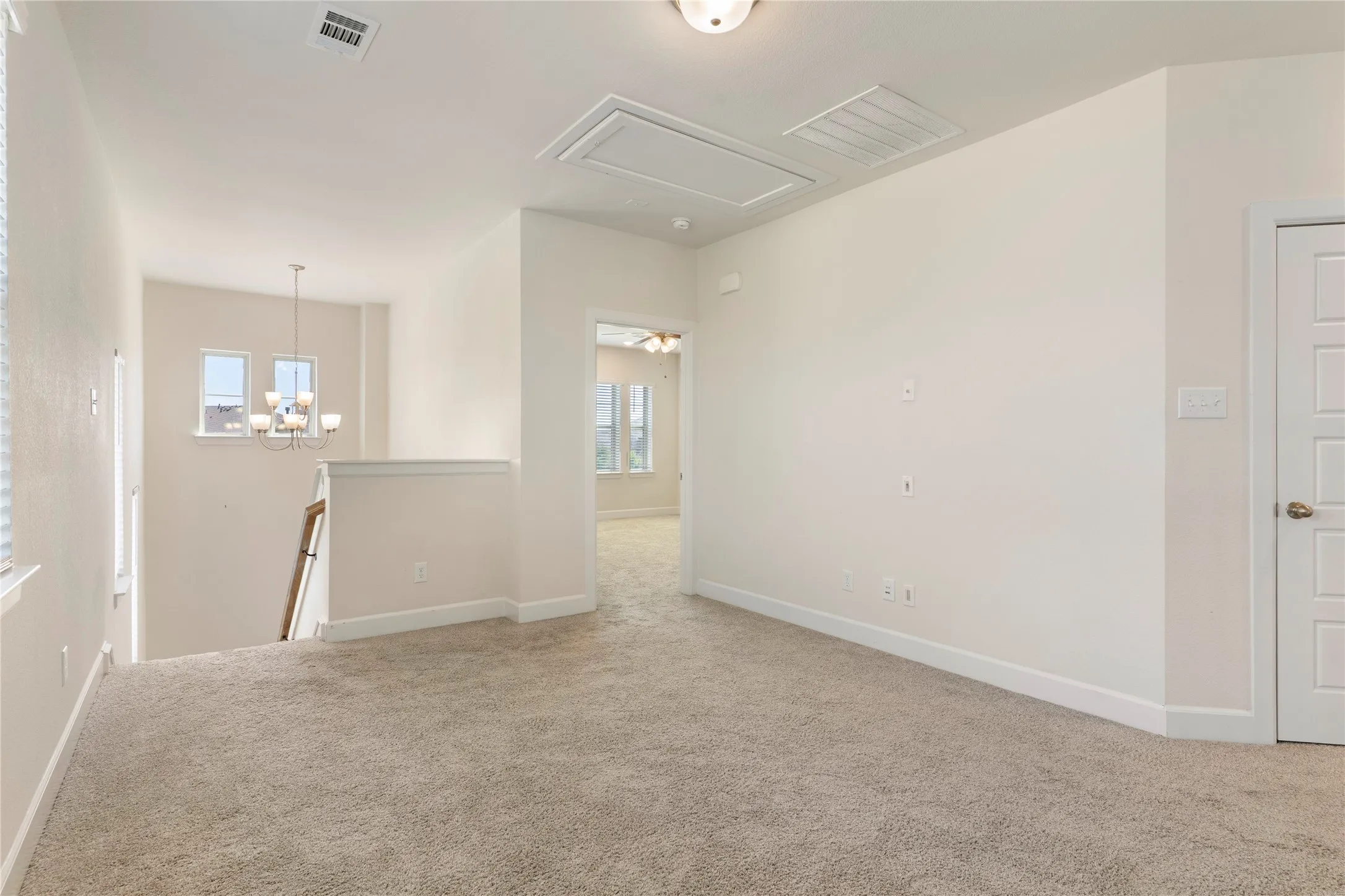 Carpeted loft area with recessed lighting, a five-panel interior door, and a banister overlooking a lower level