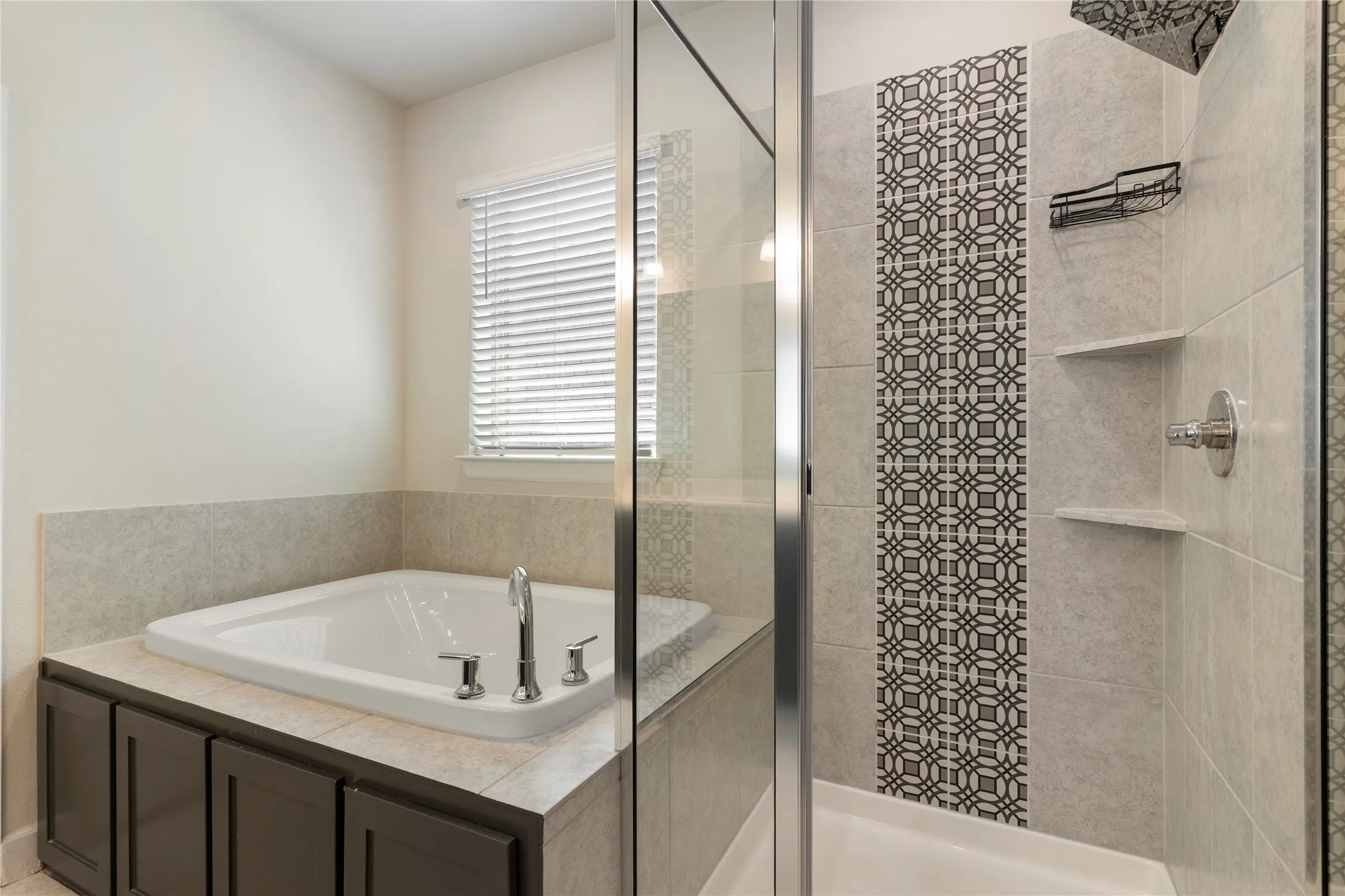 Built-in soaking tub with chrome fixtures, tiled surround, and dark wood-finish cabinetry