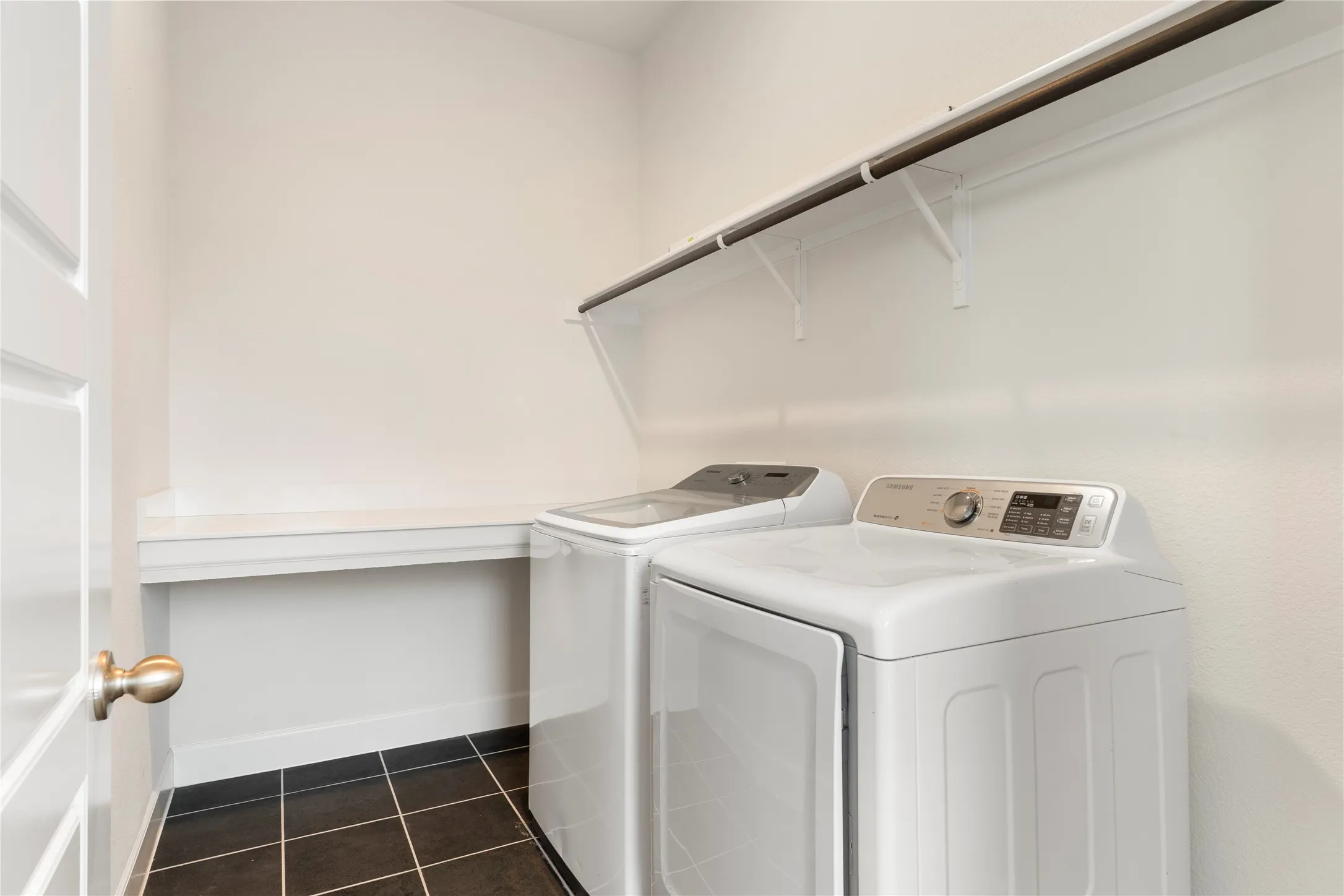 Built-in countertop, white shelving, and dark tile flooring