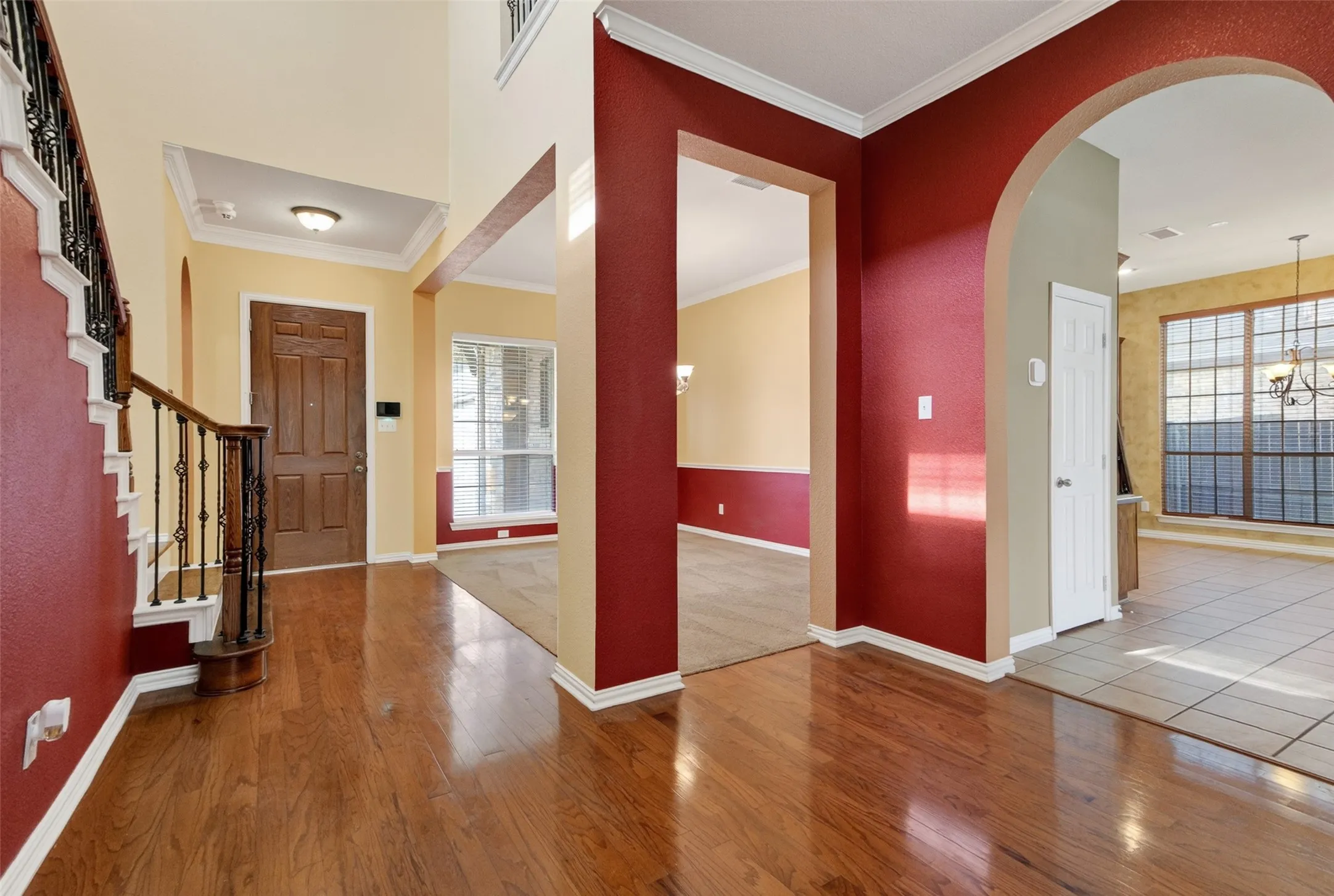 Two-story entry foyer featuring wood-finish flooring, a wood front door, and a staircase with wrought iron balusters