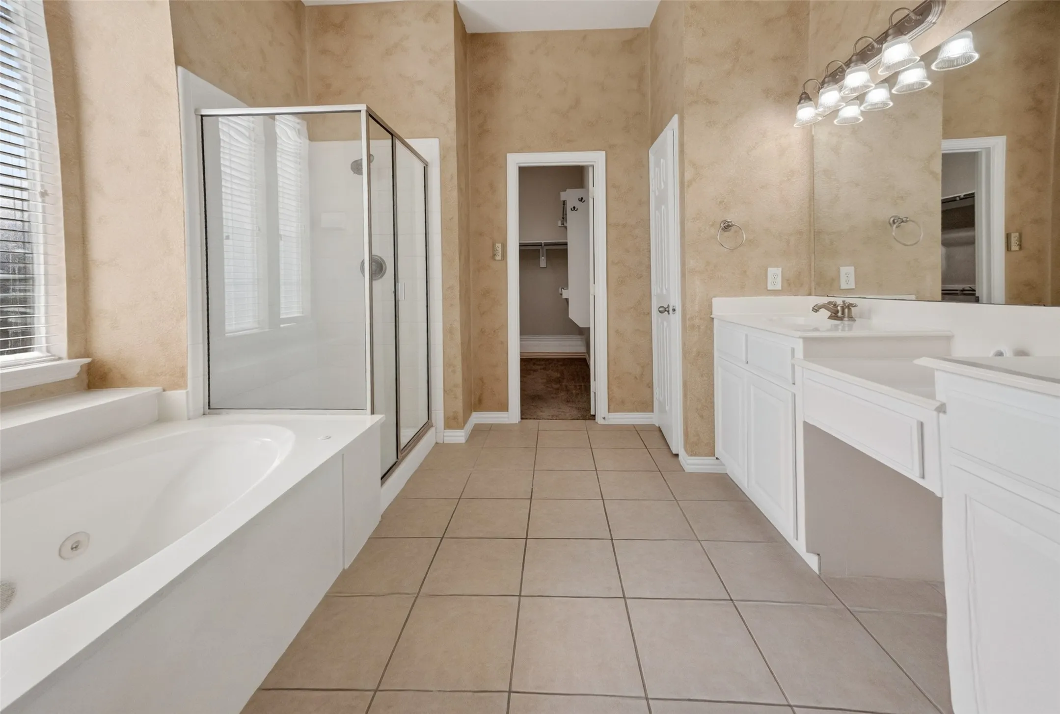 Bathroom featuring tiled flooring, a built-in soaking tub, and a separate glass-enclosed shower