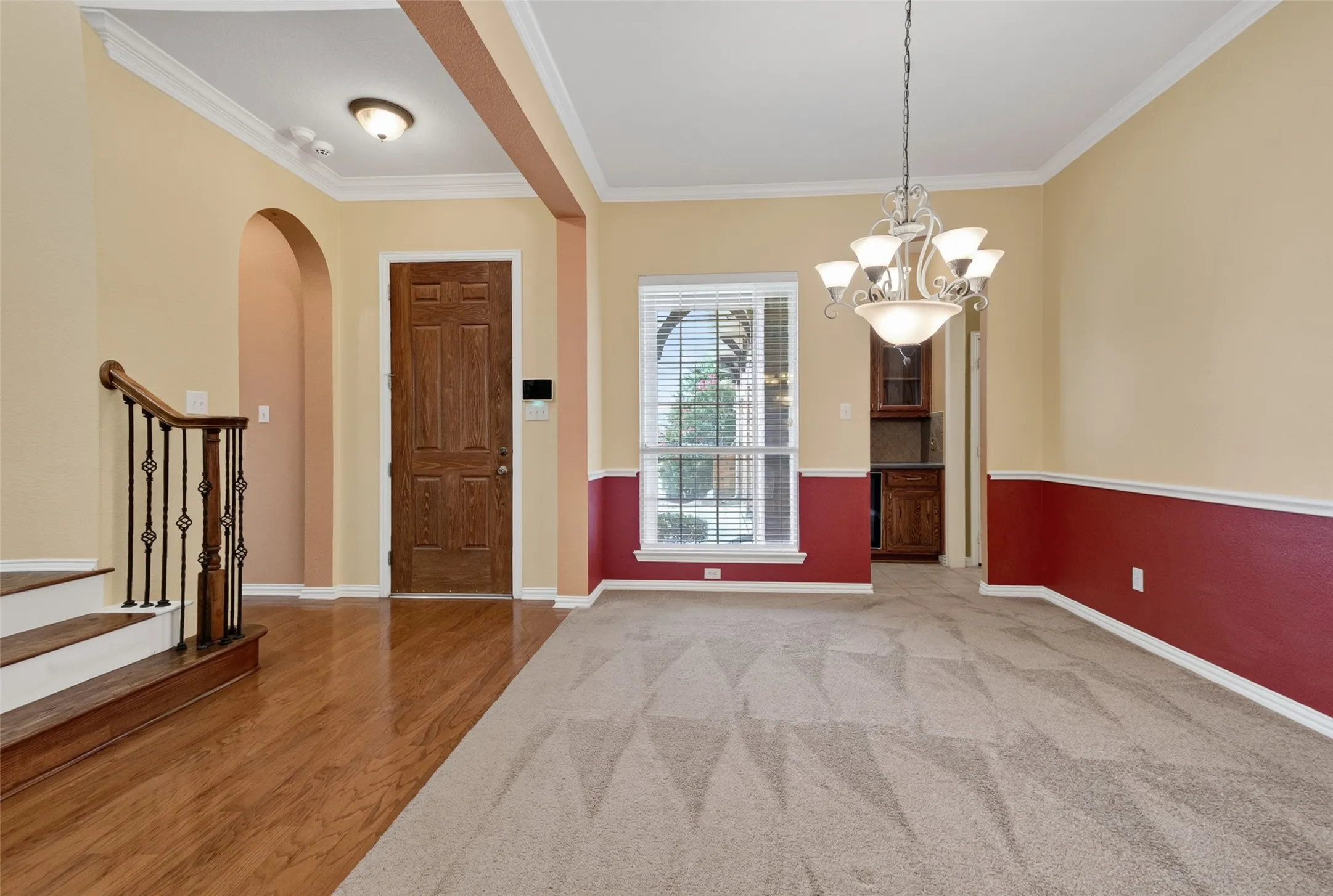 Entryway featuring a paneled wood door, wood-finish flooring, and a staircase with wrought iron balusters