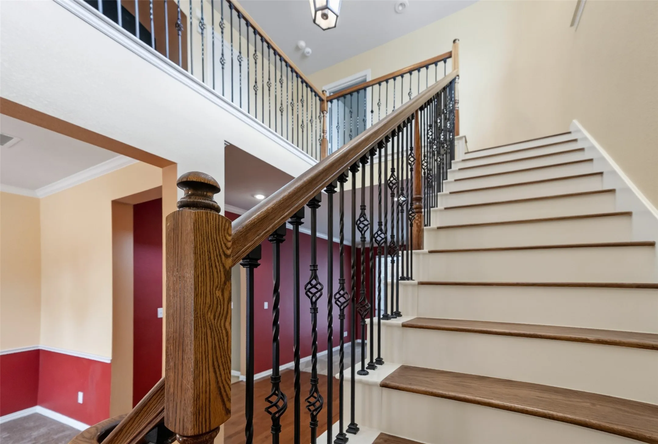 Two-story foyer featuring a wood-finish staircase with wrought iron balusters, wood-finish treads, and a coordinating wood-finish handrail