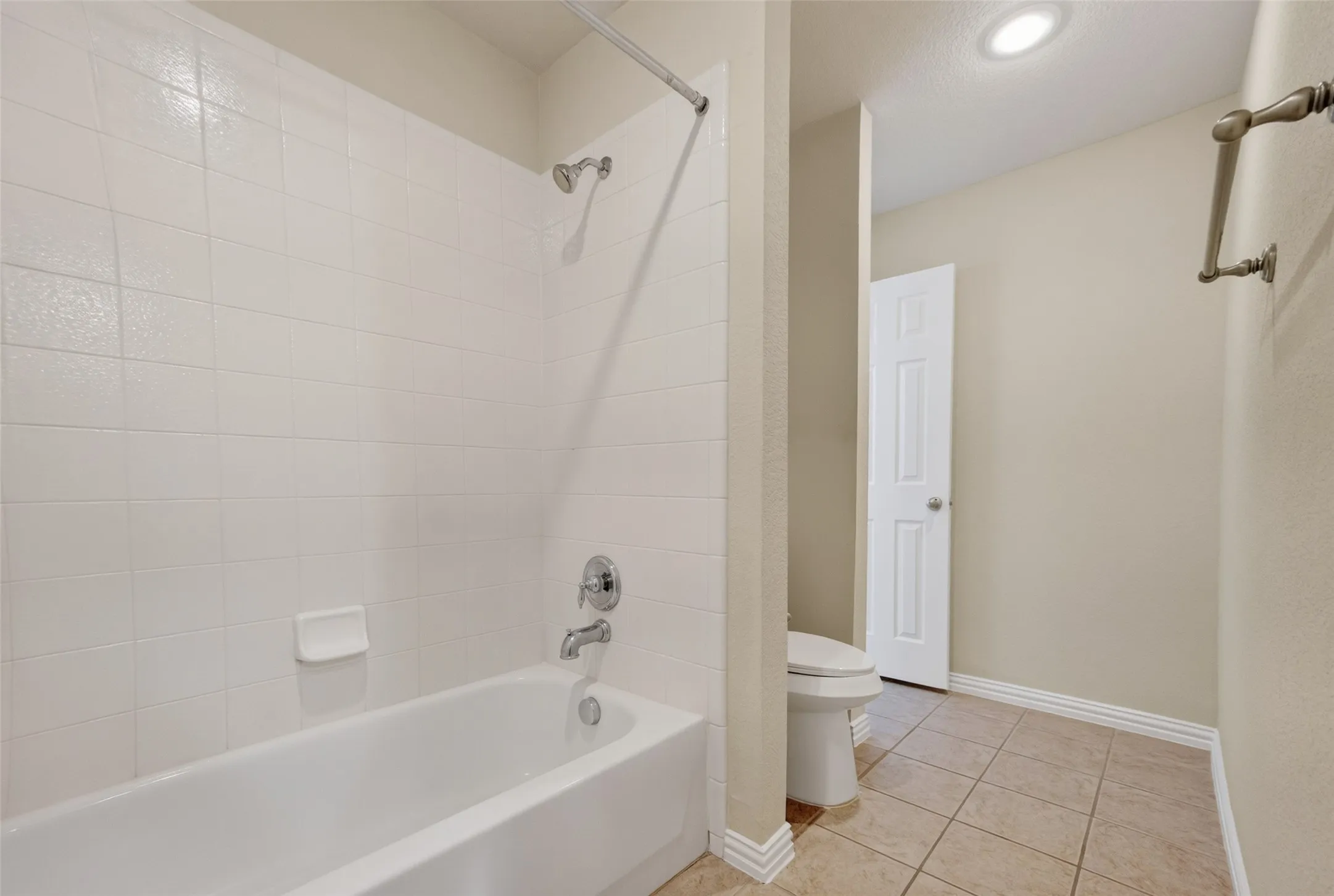 Full-size bathtub with white subway tile surround and chrome fixtures