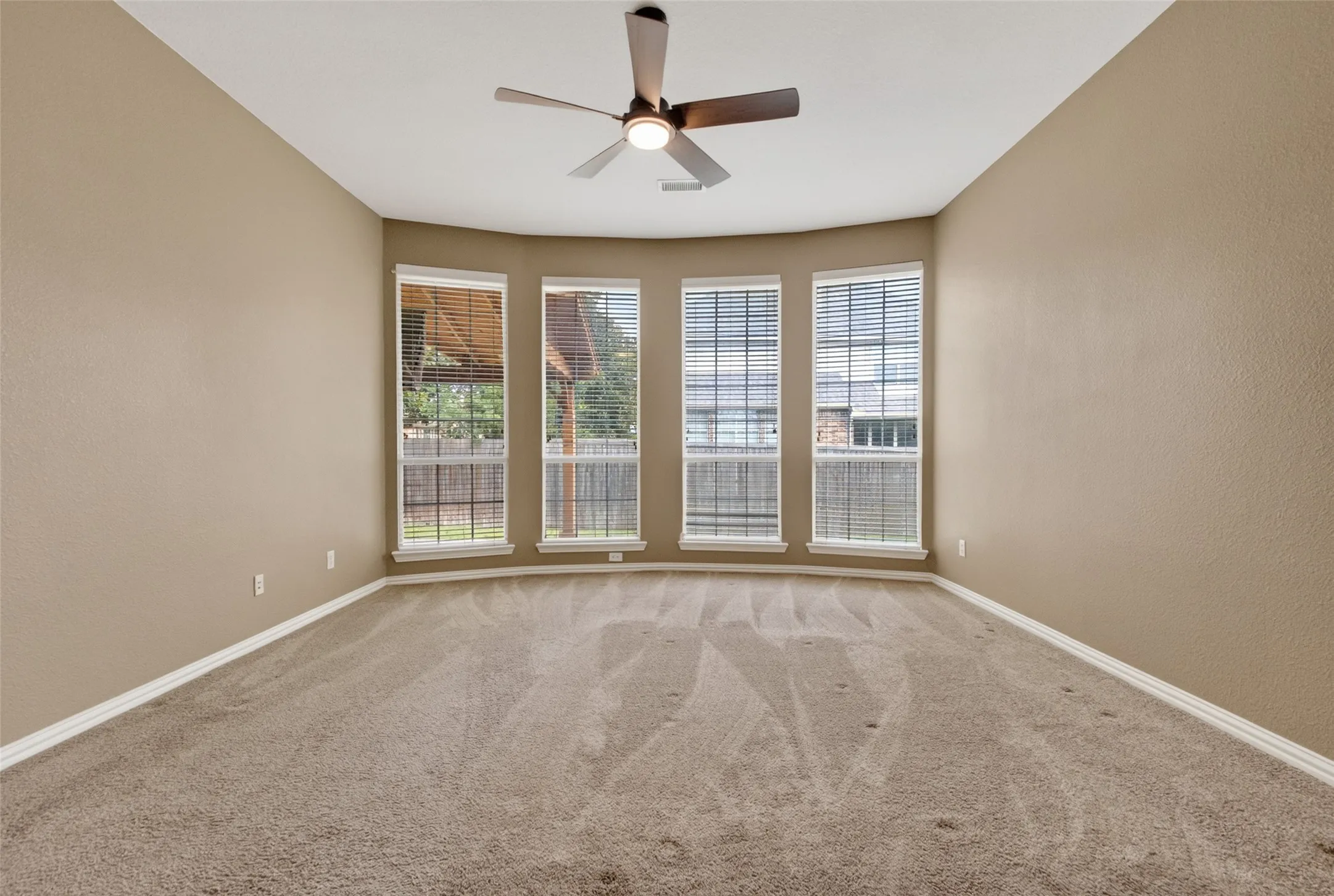 Recessed bay window with four individual windows, each featuring horizontal blinds (1st floor)