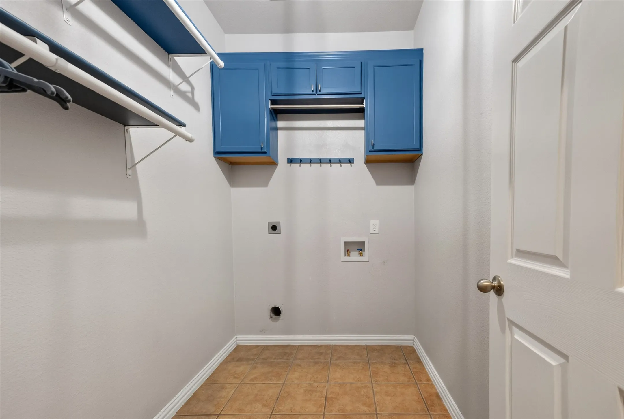 Laundry area featuring blue cabinetry, a hanging rod, and wall-mounted shelving